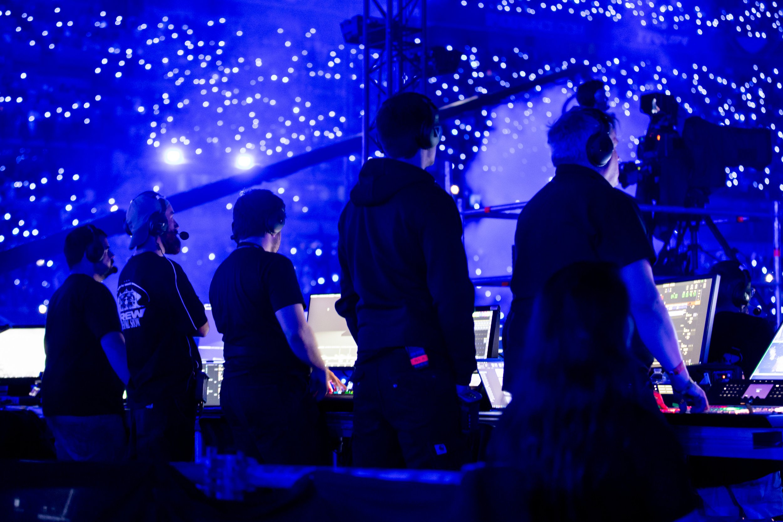 Groupe de personnes en train de mixer de la musique en studio, avec un fond de lumières bleues et blanches.