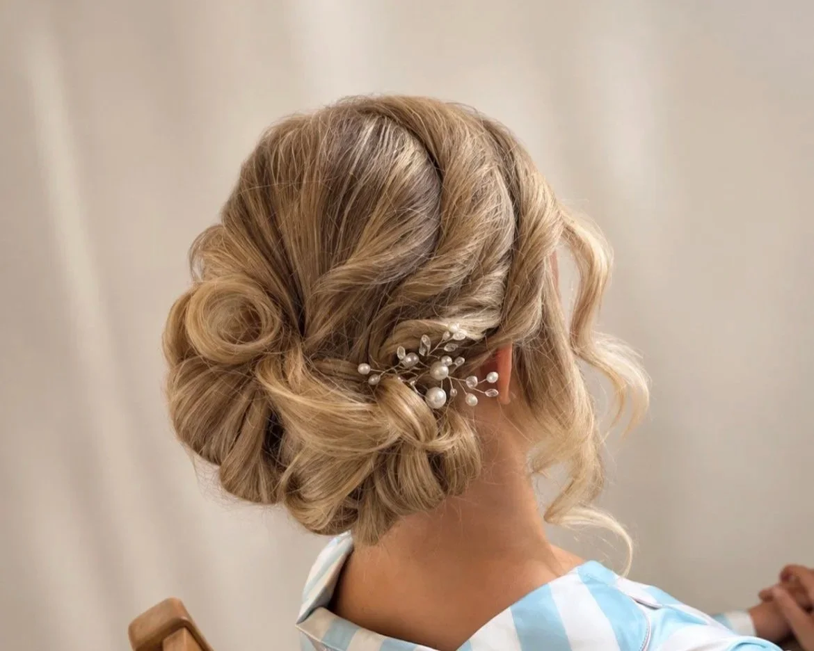 Women with blonde hair styled in an elegant updo decorated with pearl and bead hair accessories
