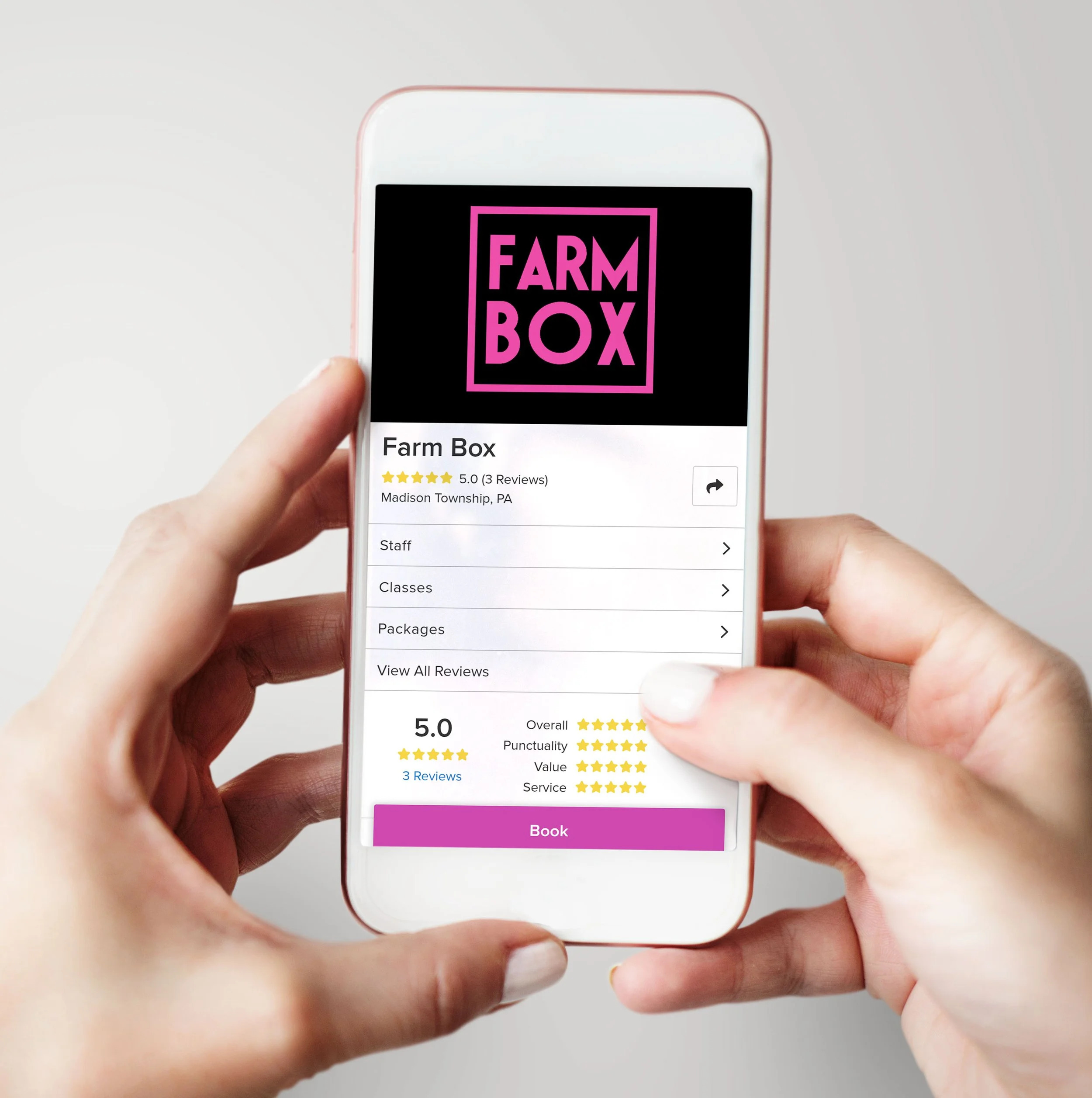 Person holding a smartphone displaying a product review for 'Farm Box' with a five-star rating and options to book, view reviews, and see details, against a plain white background.