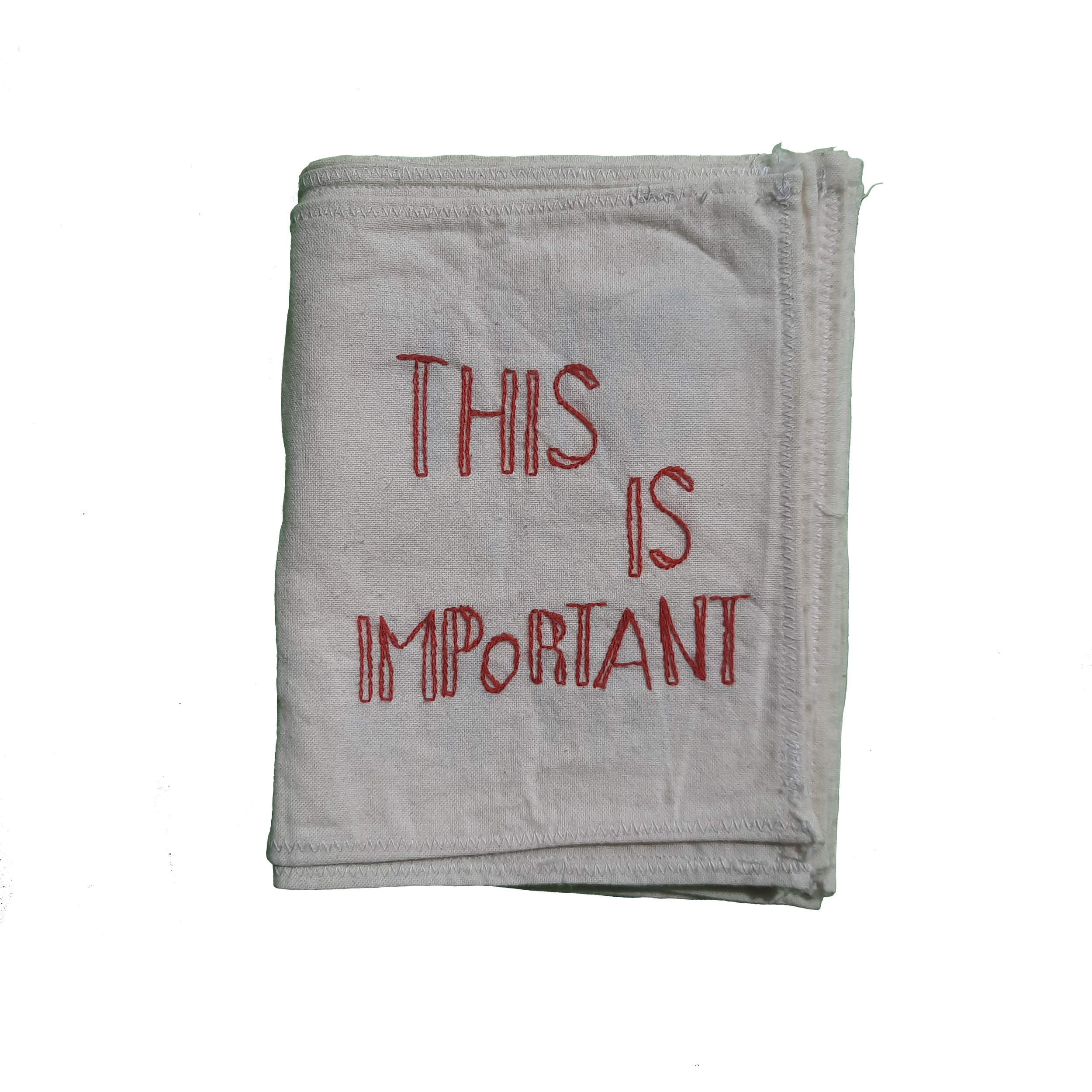 Close-up of a white cloth towel with red embroidered text reading "THIS" and part of additional text visible.