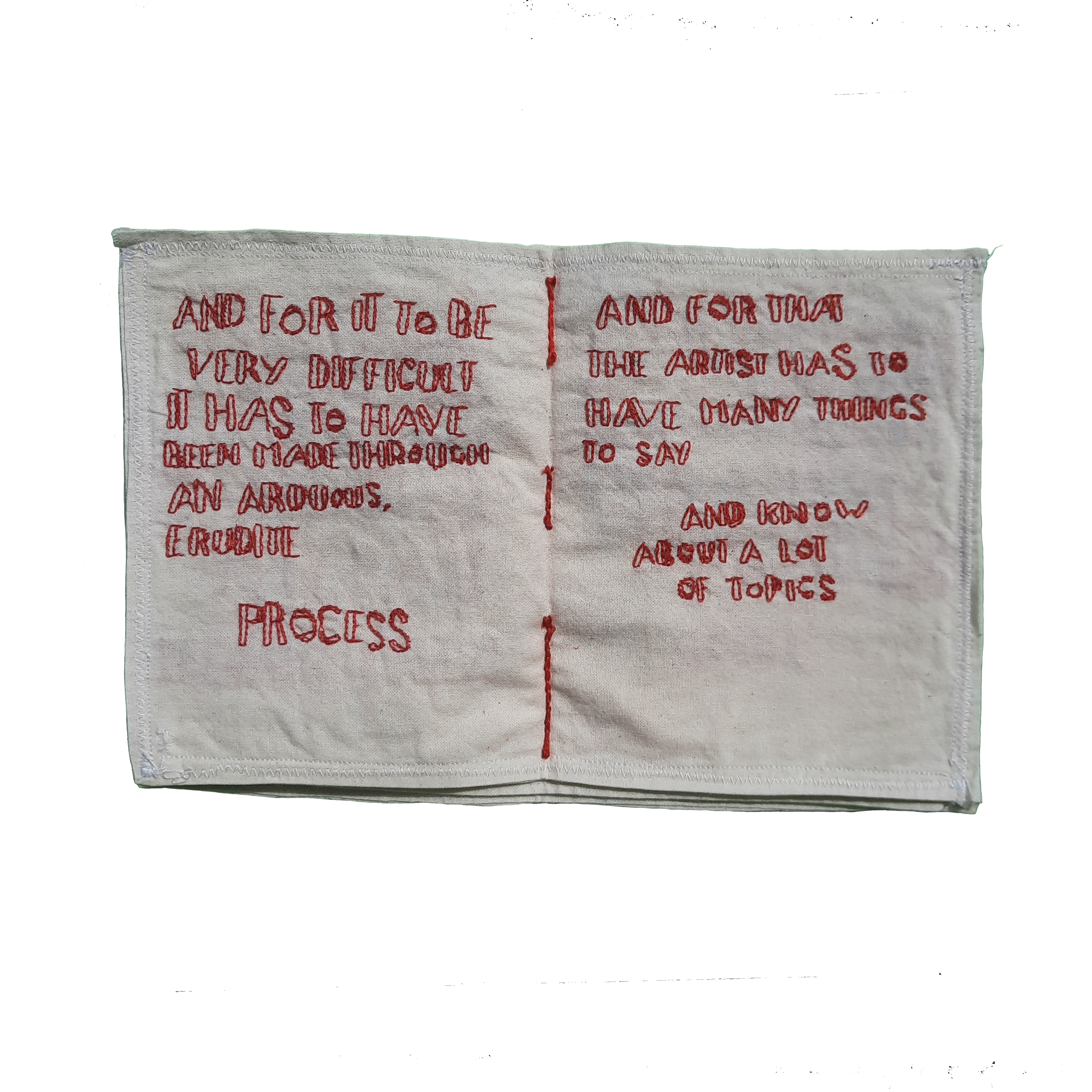 A piece of beige fabric or cloth with red embroidered text on it. The visible part of the text reads: "AND FOR IT TO BE VERY DIFFICULT." The fabric has a decorative stitched border at the top and bottom.