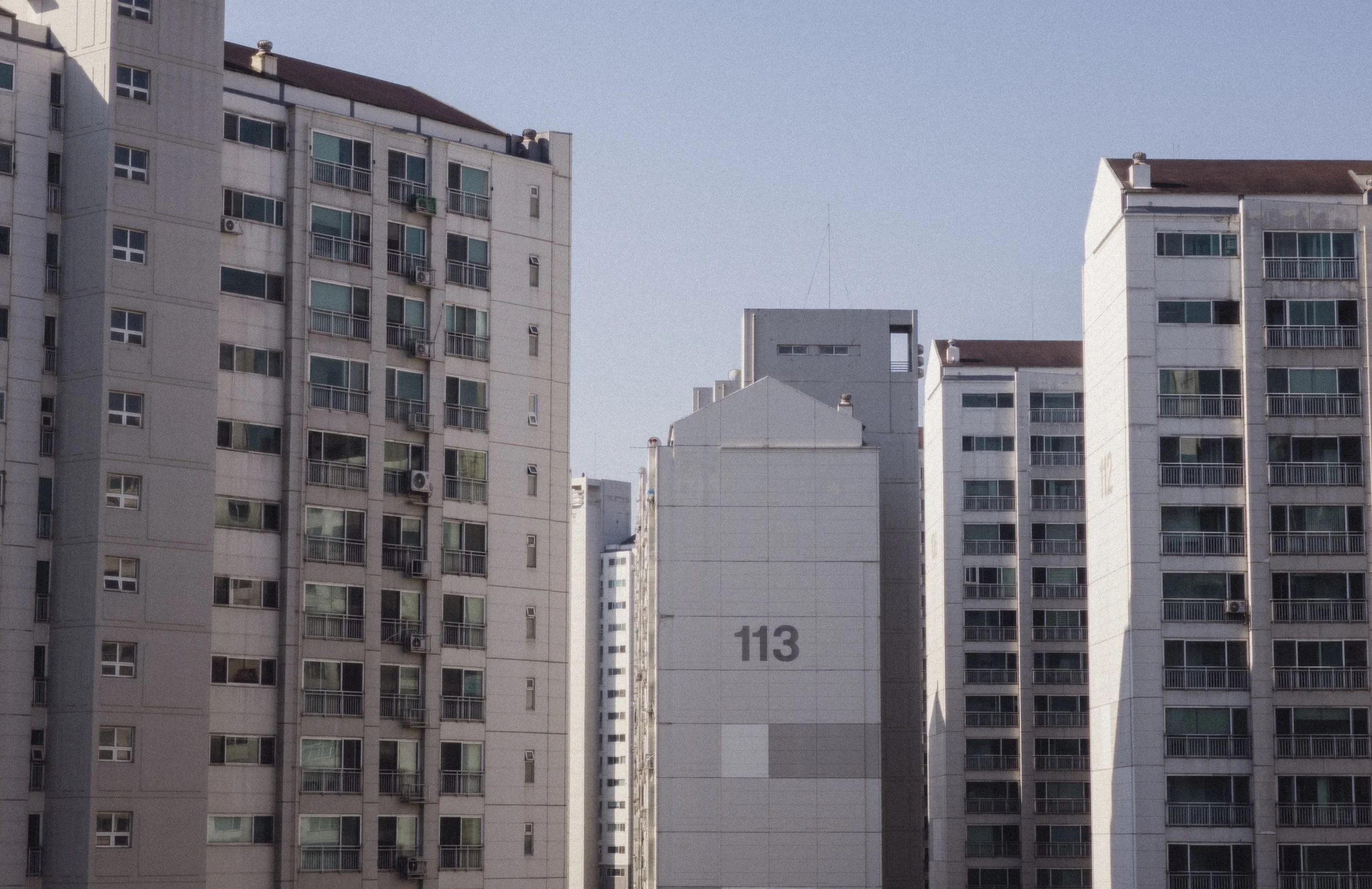 A view of several multi-story apartment buildings, with one building having the number 113 on it.
