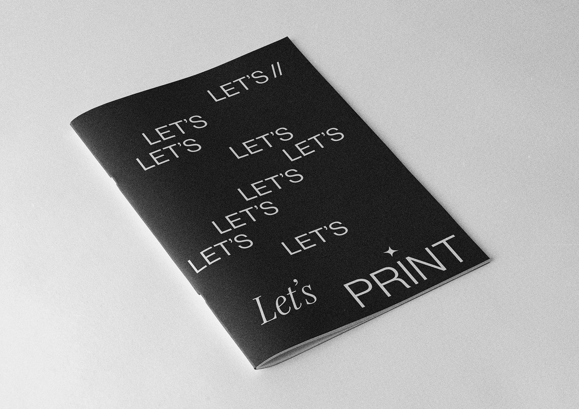 Close-up of a black and white printed booklet with multiple repetitions of the phrase "LET'S" and the phrase "LET'S PRINT" at the bottom.