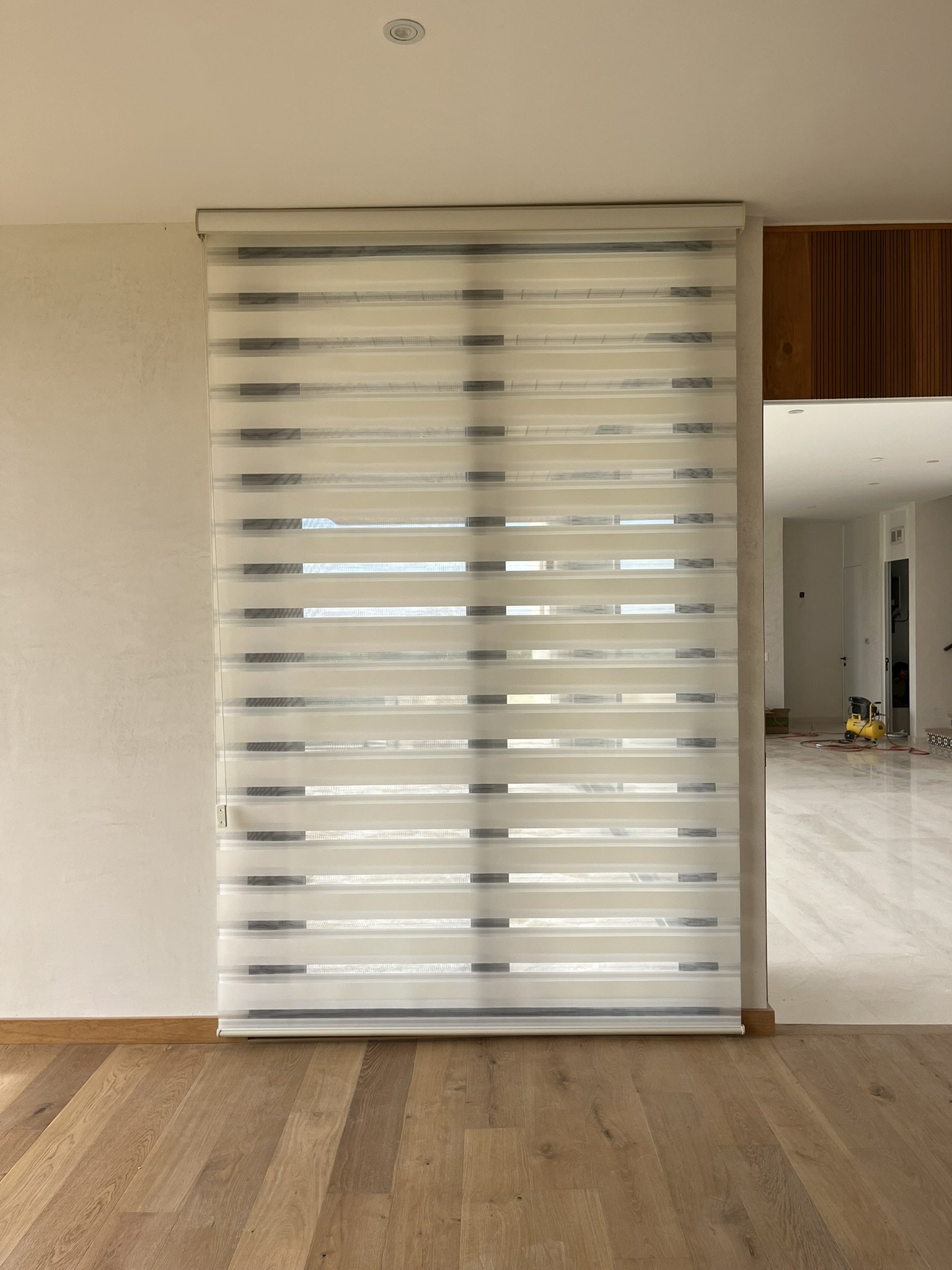 Puerta con persiana estilo Sheer Elegance en un espacio interior, decorada con paredes blancas y un acabado de piso de madera. Dentro de una casa en San Miguel de Allende.
