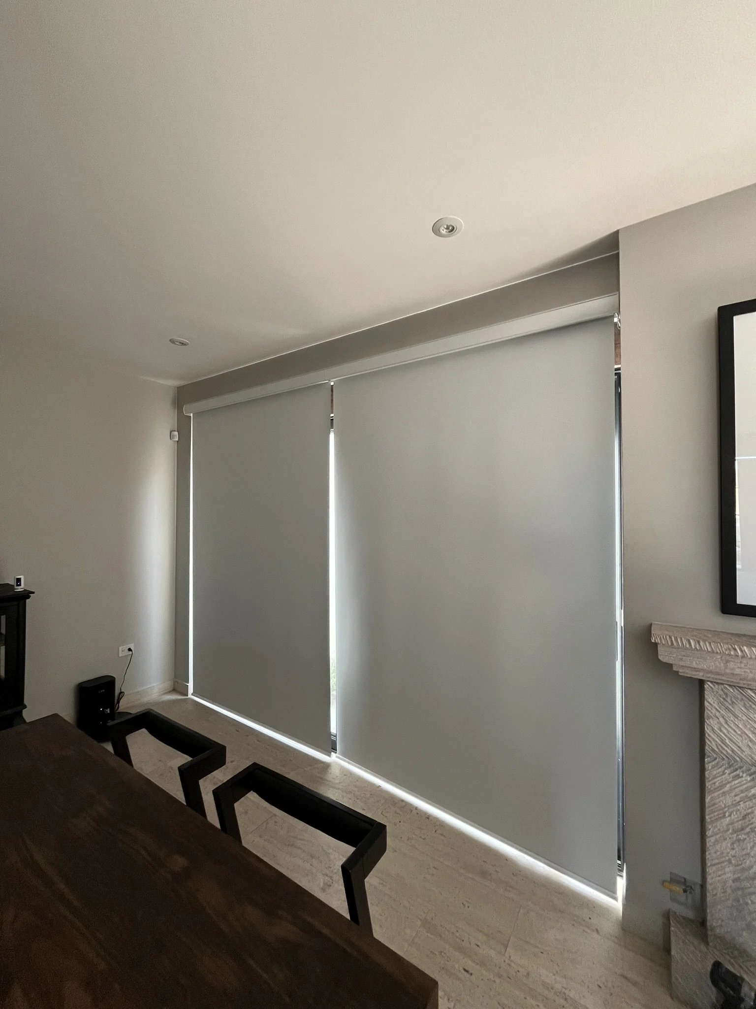 Sala de estar con ventanas con cortinas enrollables blancas estilo blackout, paredes beige y suelo de madera clara. Frente a las ventanas hay una mesa de comedor de madera oscura con sillas del mismo color. Casa ubicada en San Miguel de Allende