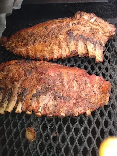 Two grilled fish steaks cooking on a mesh grill.