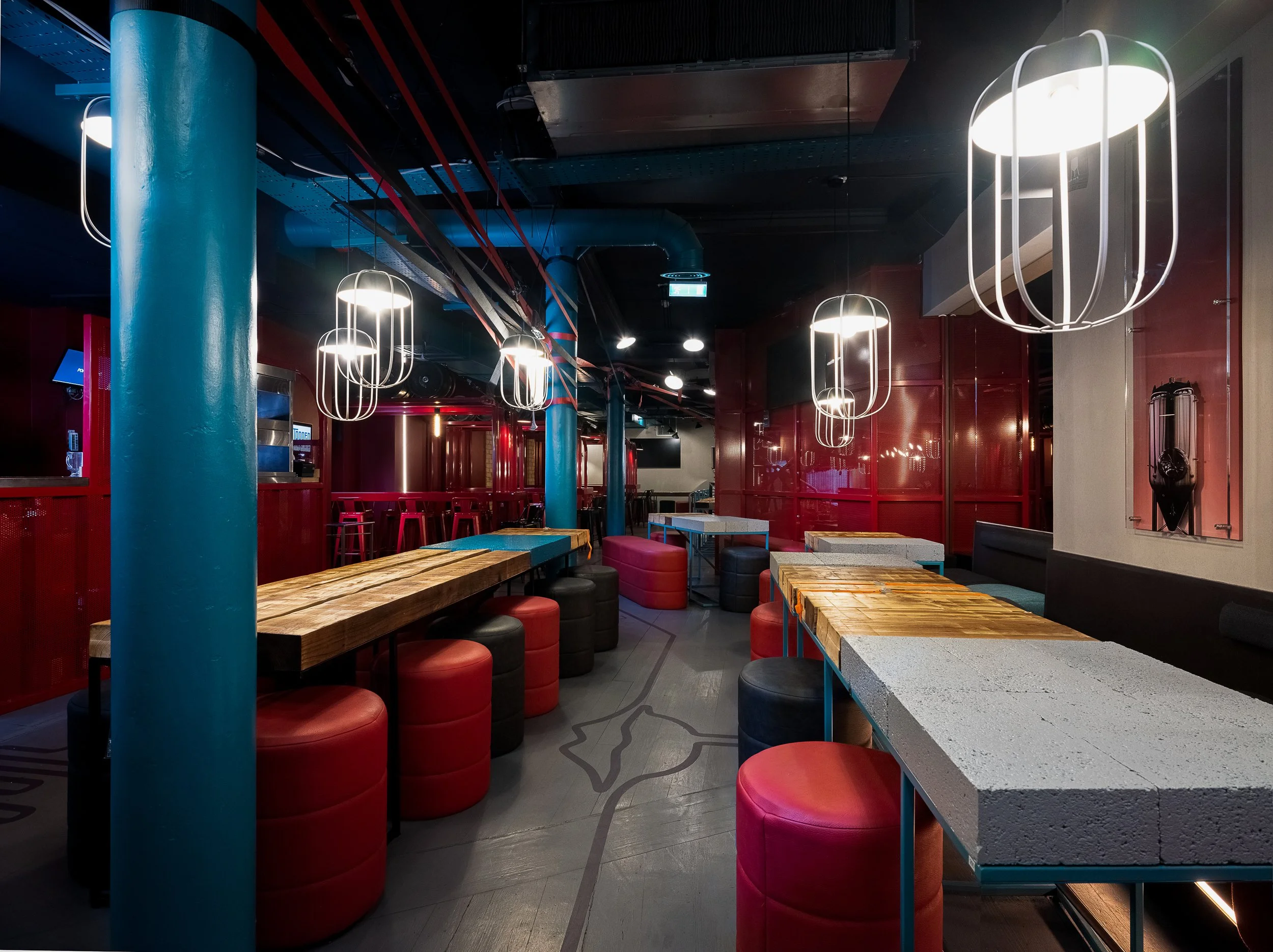 Tapped, Grafton Street, Dublin — Interior view of a modern, stylish lounge or cafe with red and blue decor, featuring hanging lights, tables, and round seats.