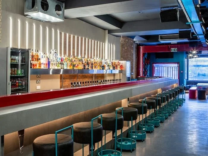 Tapped, Grafton Street, Dublin — Modern bar with a long counter, high stools, and liquor bottles on illuminated shelves.