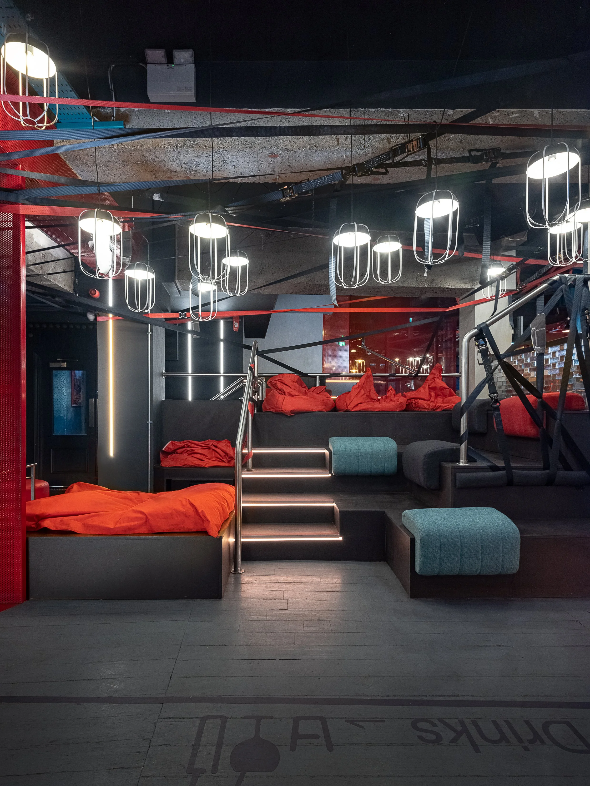 Tapped, Grafton Street, Dublin — Tiered lounge seating with red cushions, hanging lights and an exposed industrial ceiling.