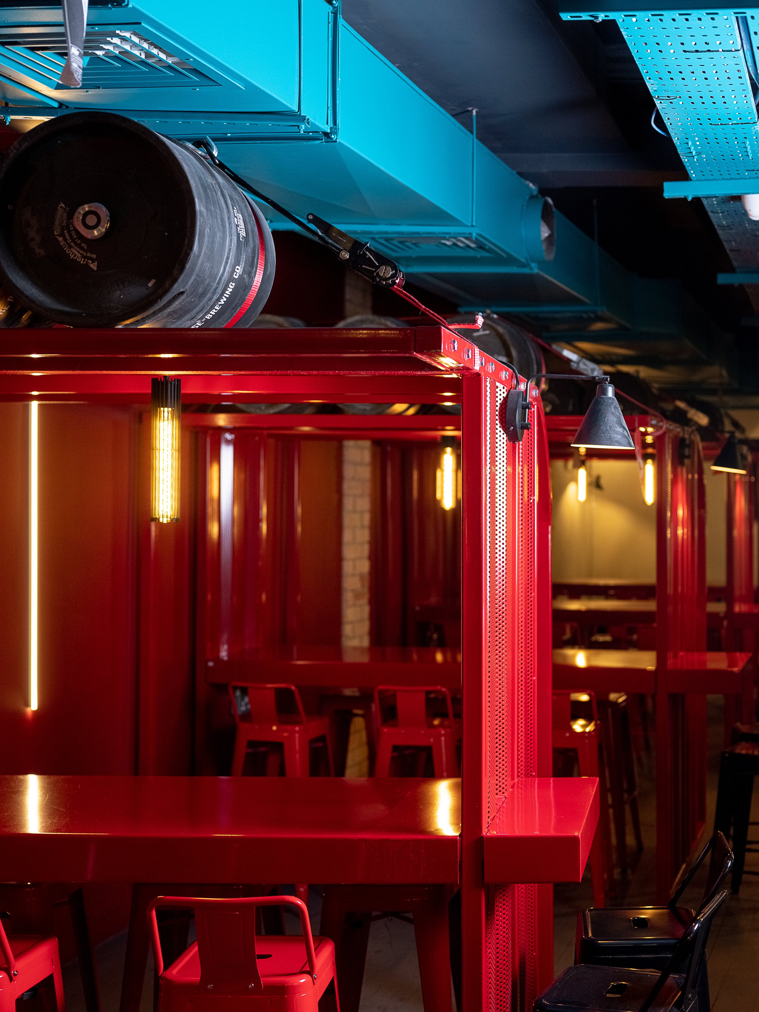 Tapped, Grafton Street, Dublin — Interior of a restaurant or bar with red booths, hanging black pendant lights, and colorful industrial-style ceiling fixtures.