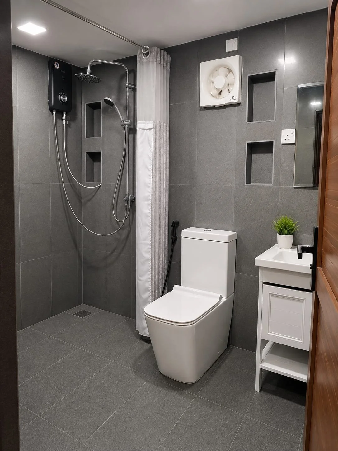 Modern bathroom featuring a walk-in shower with a black water heater, a white toilet, a small white sink with a potted plant, and built-in wall niches on dark gray tiled walls.