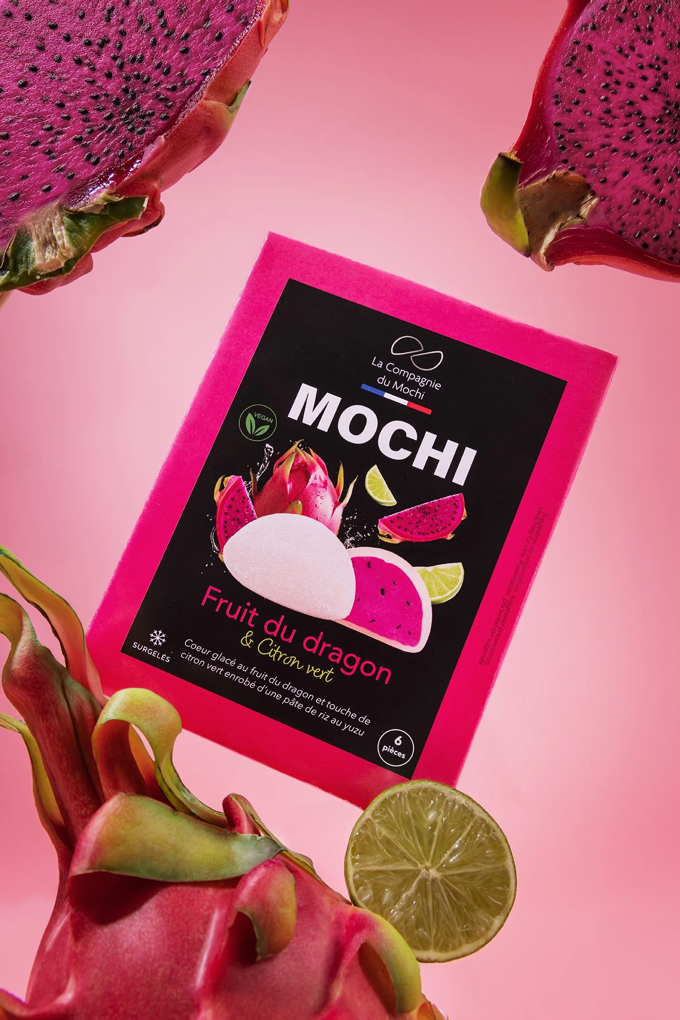 Gros plan d'un fruit du dragon et un citron vert, avec un emballage de glaces à base de fruit du dragon et citron vert, sur un fond rose