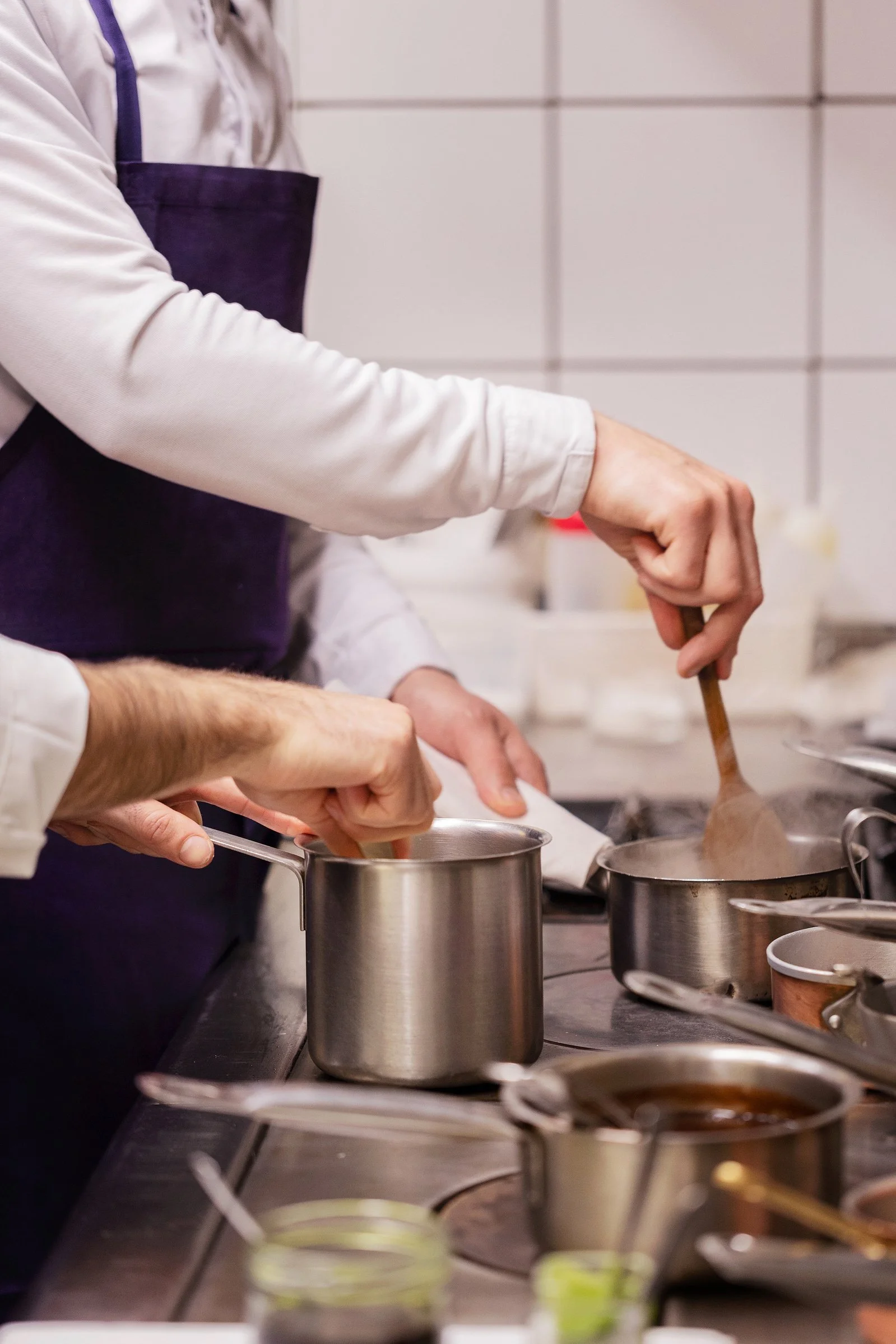 Cuisiniers en train de préparer des plats dans une cuisine professionnelle, utilisant des casseroles sur la cuisinière.