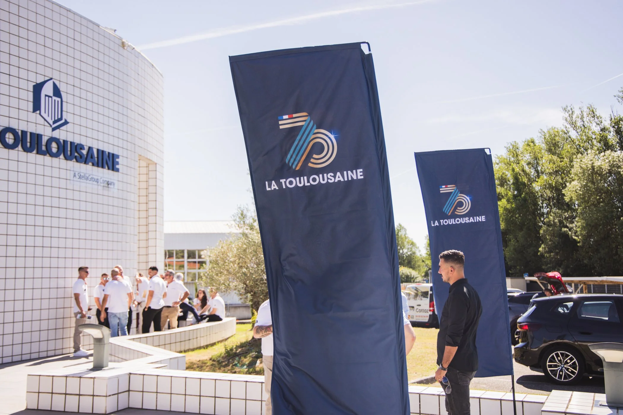 Étudiants réunis à l'extérieur devant un bâtiment, avec des banderoles portant le logo et le nom 'La Toulousaine'.