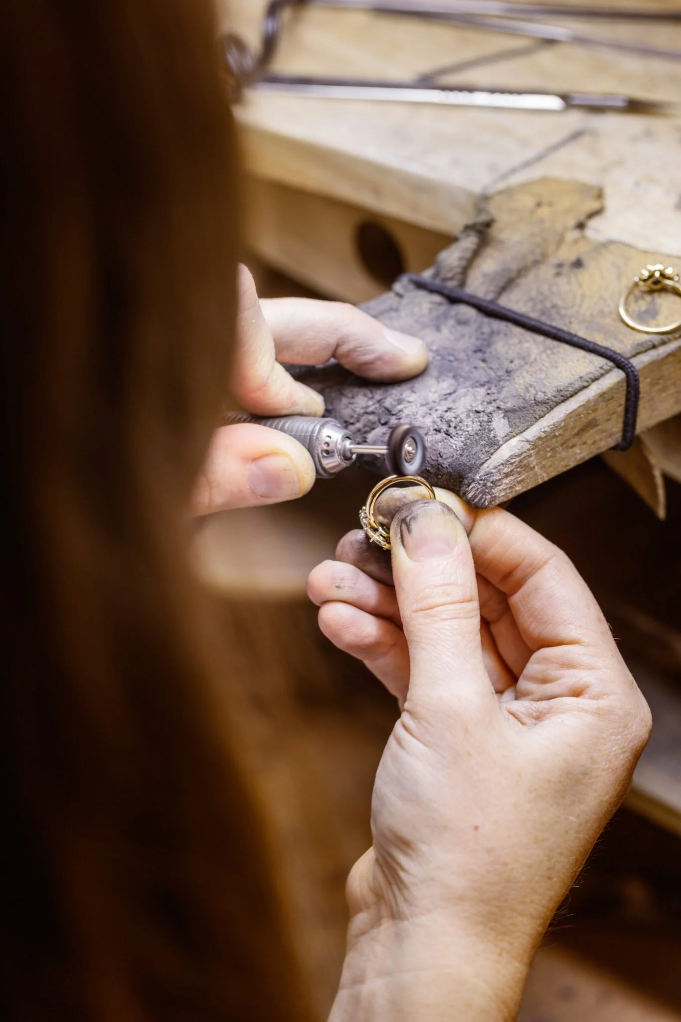 Une personne travaille sur la mise à jour ou la réparation d'une bague en or, utilisant une petite machine dans un environnement de bricolage ou d'atelier.