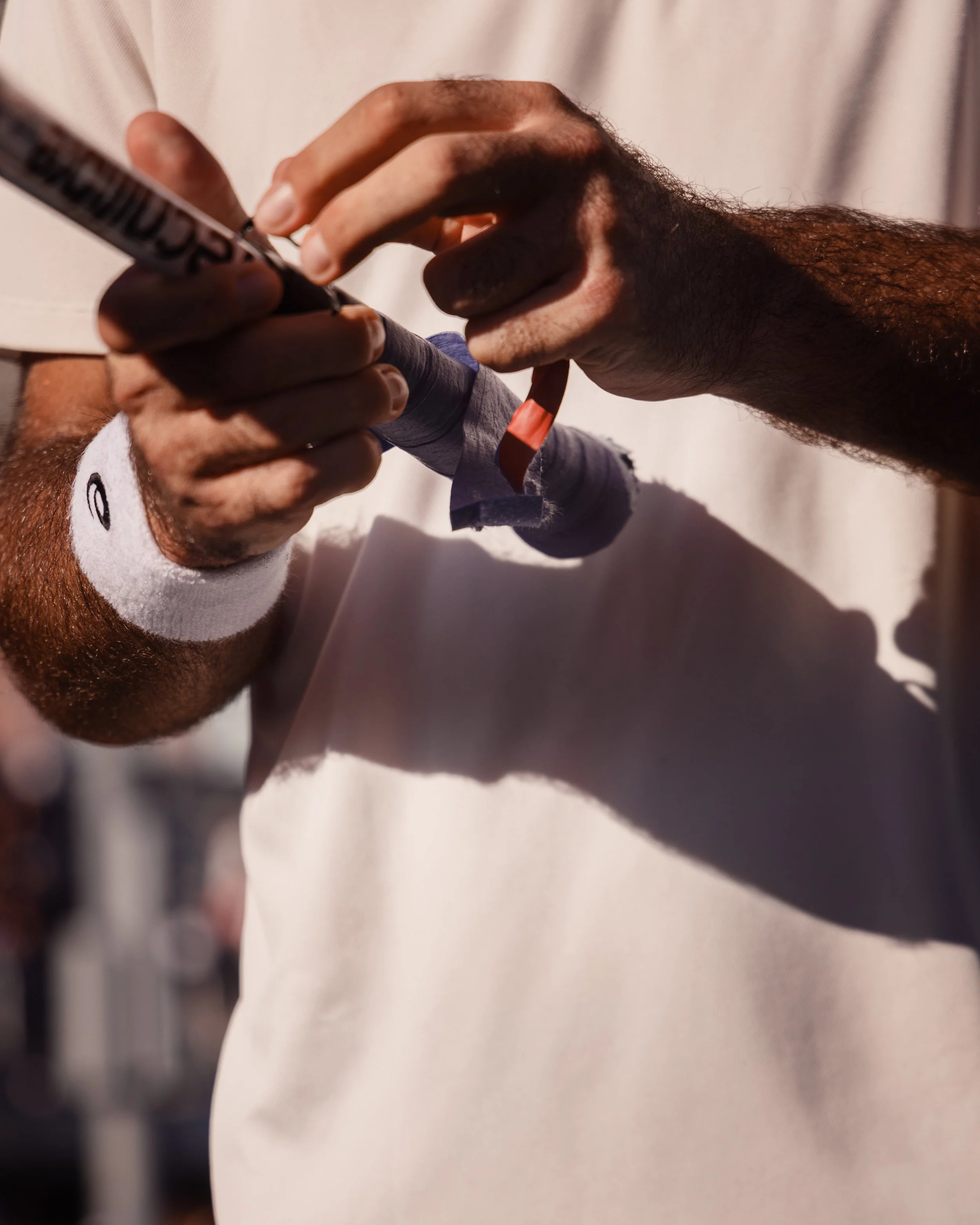 Main dans une main portant un bracelet orange et une autre main tenant un marqueur noir, en train d'écrire ou de signer sur une feuille ou un document.
