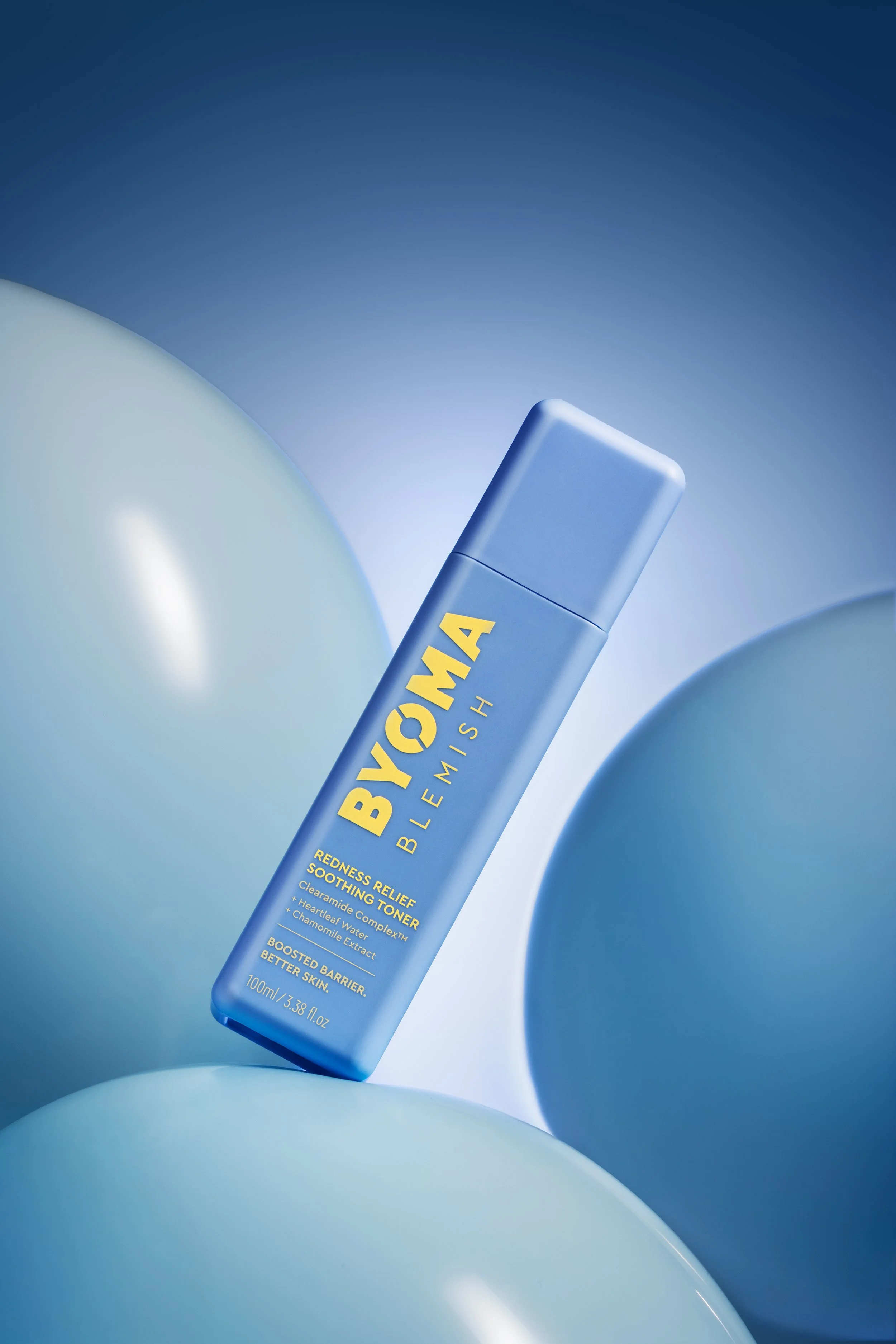 Une bouteille de tonique Byaom posée sur un fond de ballons bleus et blancs.