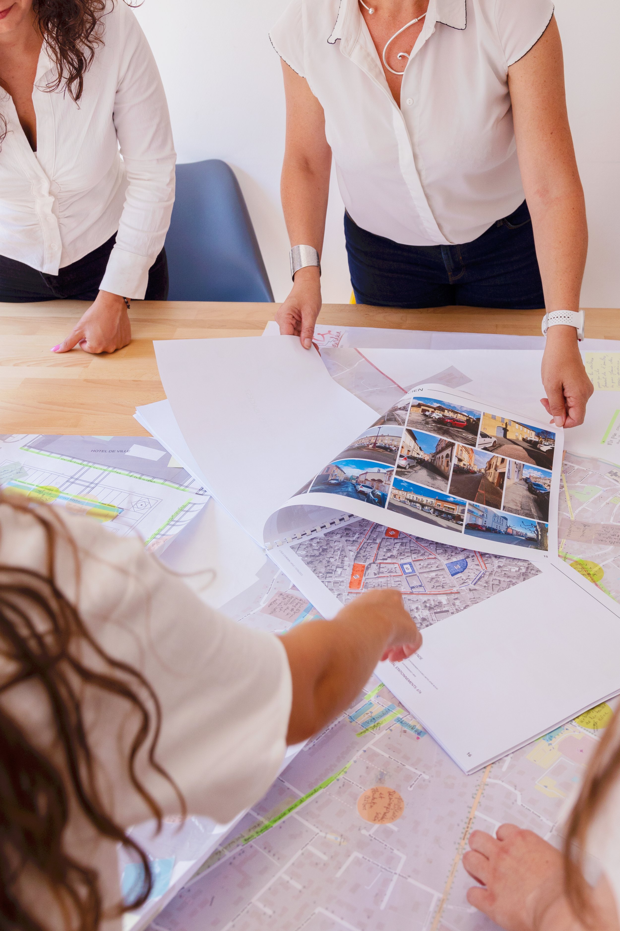 Deux femmes regardant et discutant des plans et cartes sur une table.