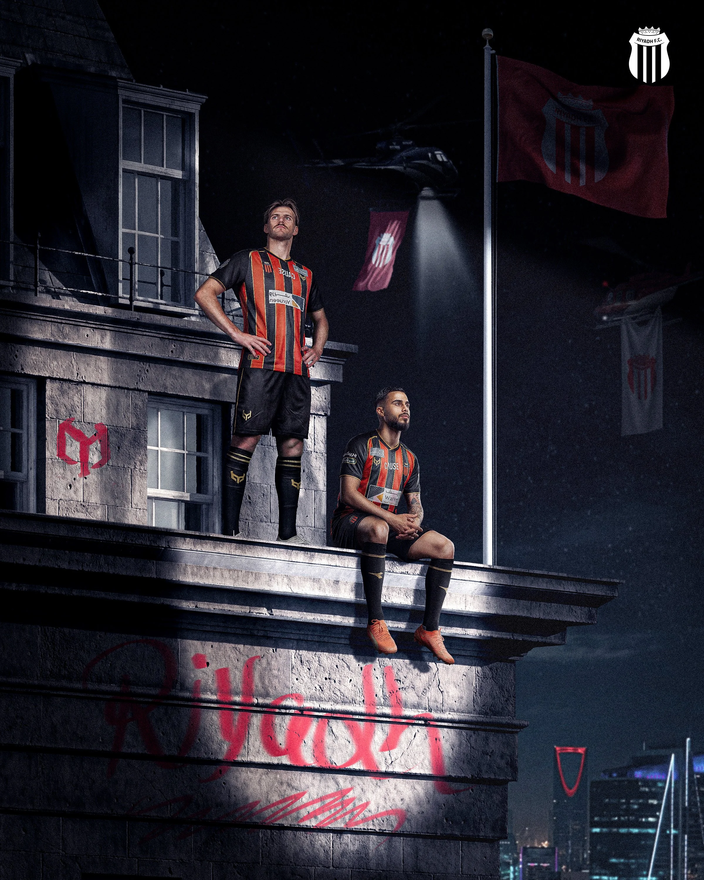 A man in a black and red striped sports jersey standing on a ledge with his hands on his hips, and another man in the same jersey sitting on the ledge with one leg crossed over the other. Both are in front of flags and a helicopter in a dark cityscap