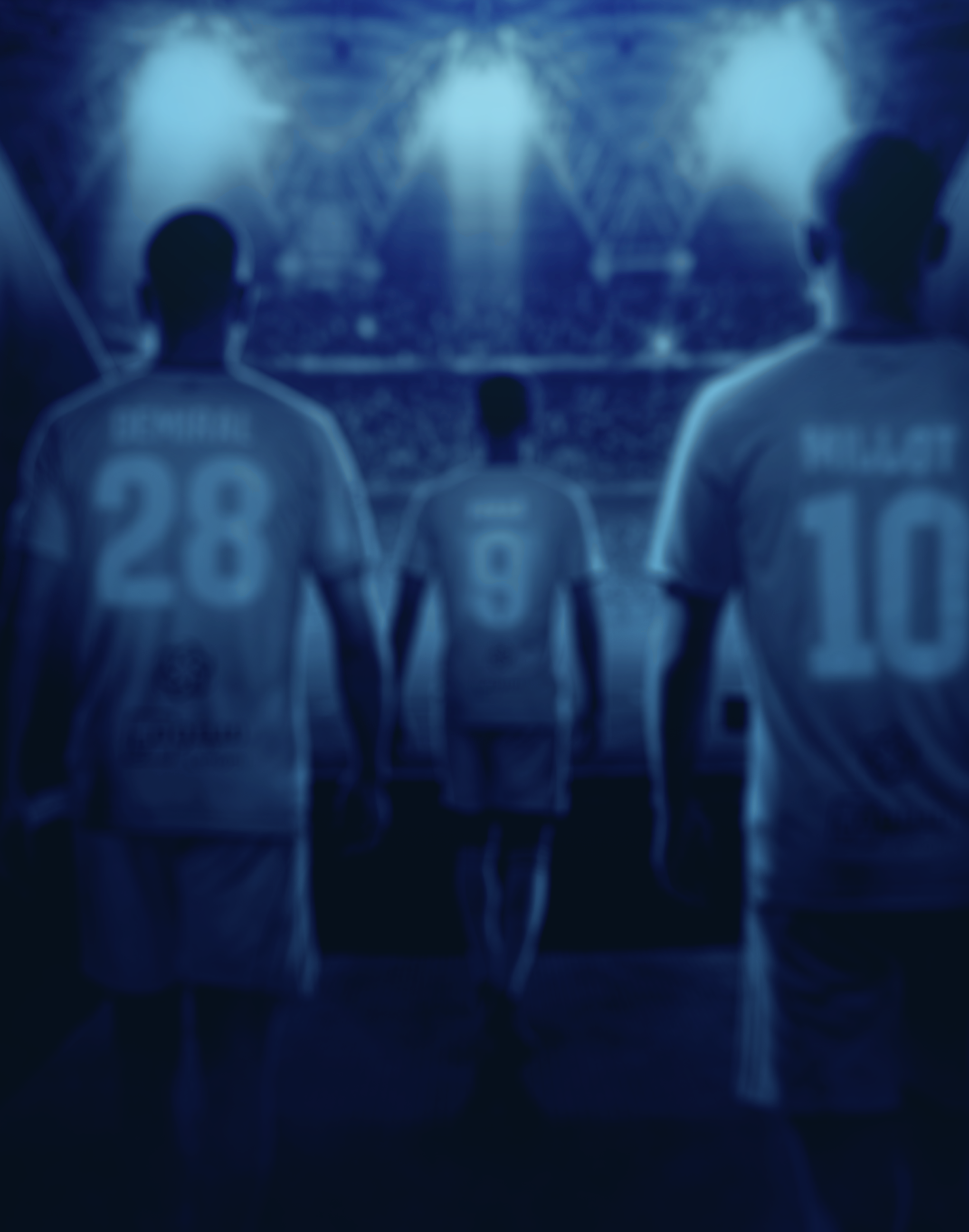 Three football players in uniform standing on a field during a game, with stadium lights and crowd in the background.