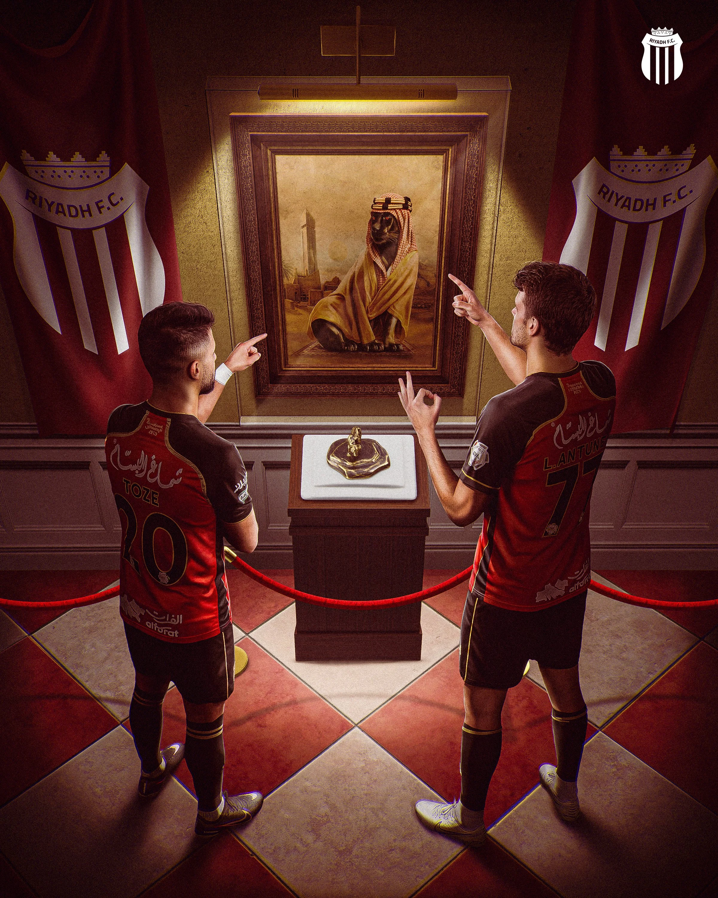 Two people dressed in FC Barcelona soccer jerseys standing in front of a framed portrait of a dog dressed in traditional Middle Eastern attire, inside a museum or gallery with Riyadh F.C. banners on the sides.