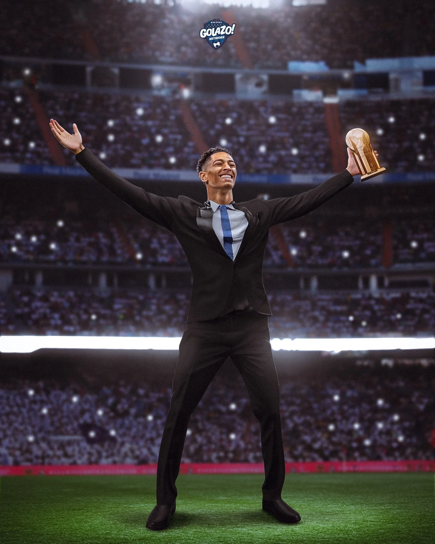A man in a suit on a sports stadium field holding a gold trophy with arms outstretched, smiling. The stadium is filled with spectators, and there is a logo that says "GOLAZO! NETWORK" at the top.