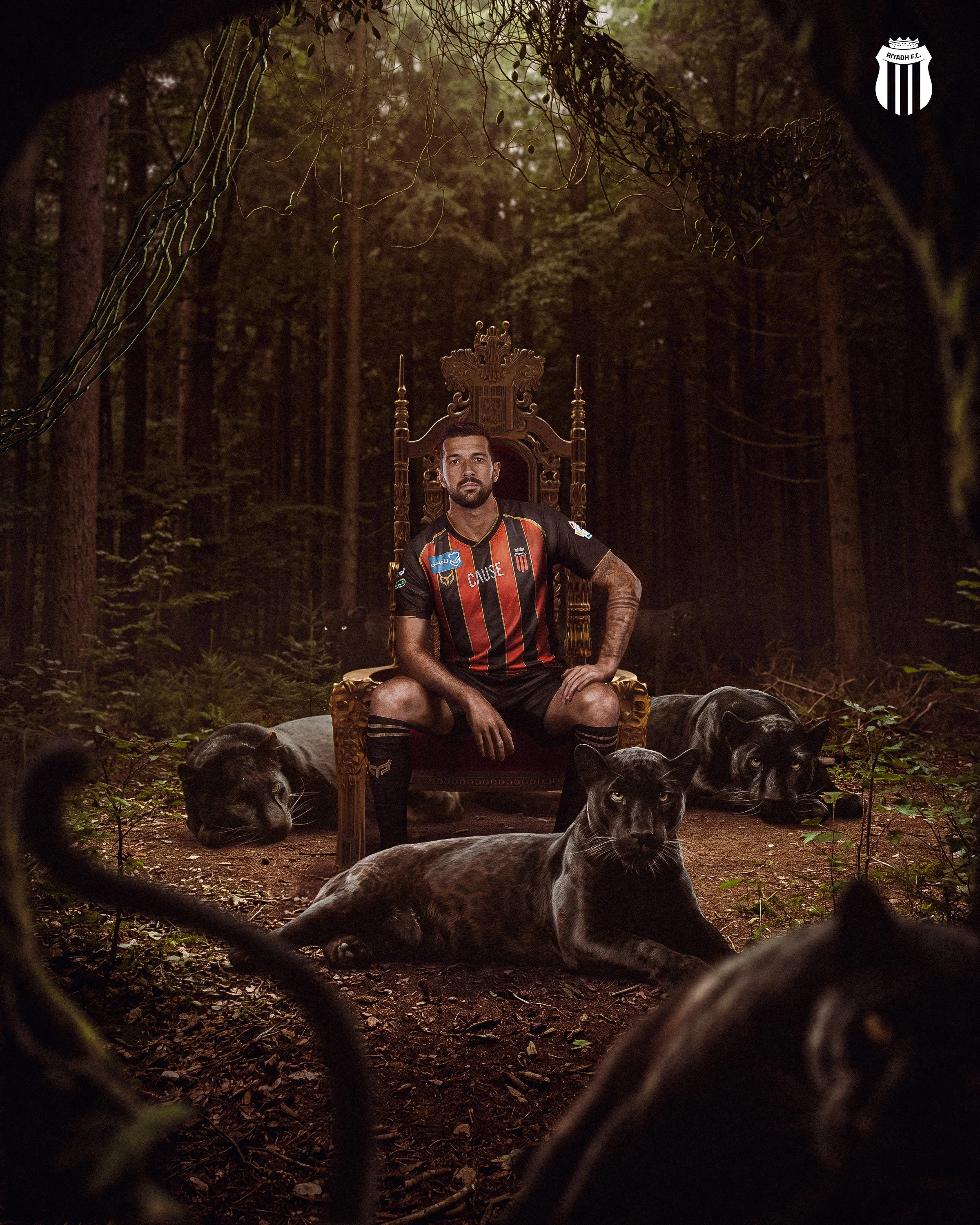 A man sitting on an ornate wooden throne in a dense forest, surrounded by black panthers, viewed through a chain-link fence.