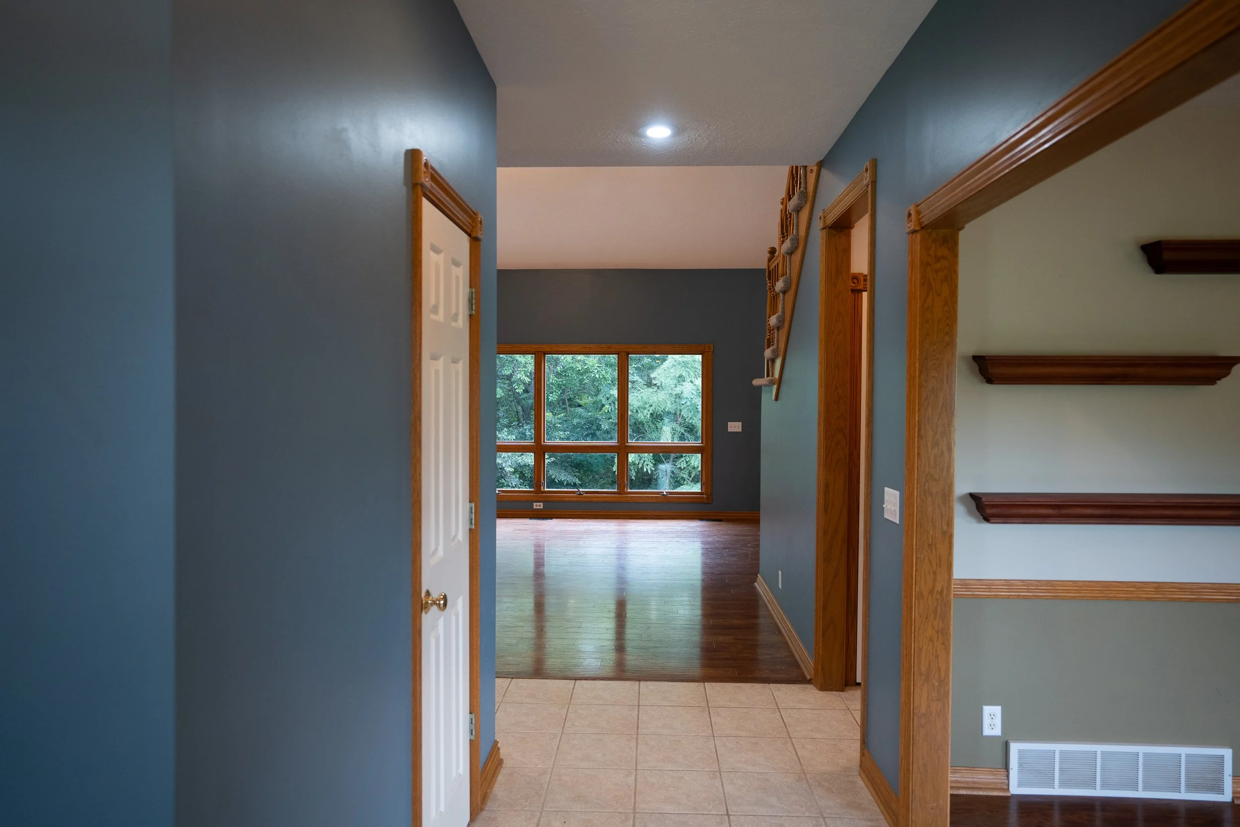 Hallway view leading into an open living room with large windows at the far end.