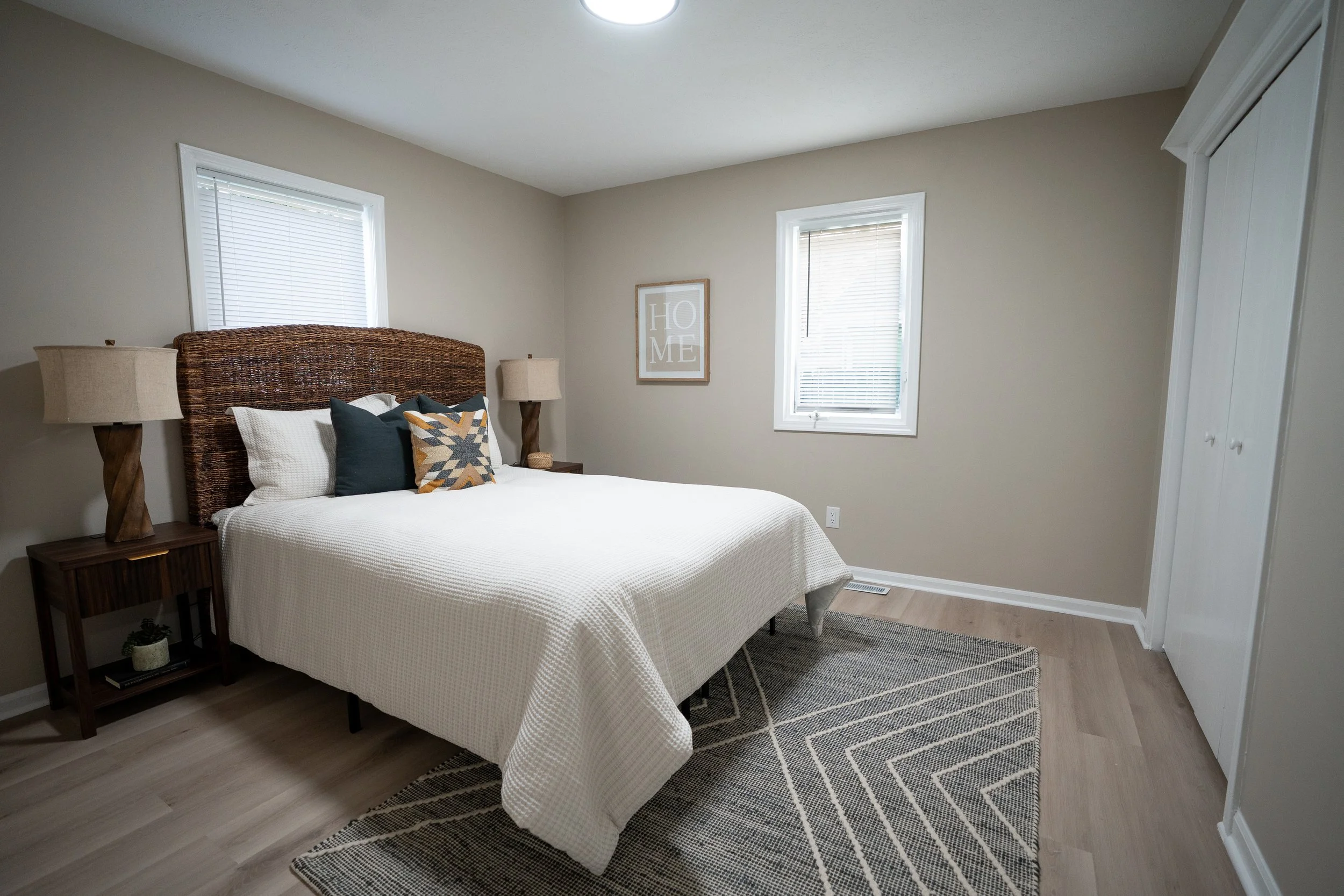 Modern bedroom with a made bed, throw pillows, and two nightstands.