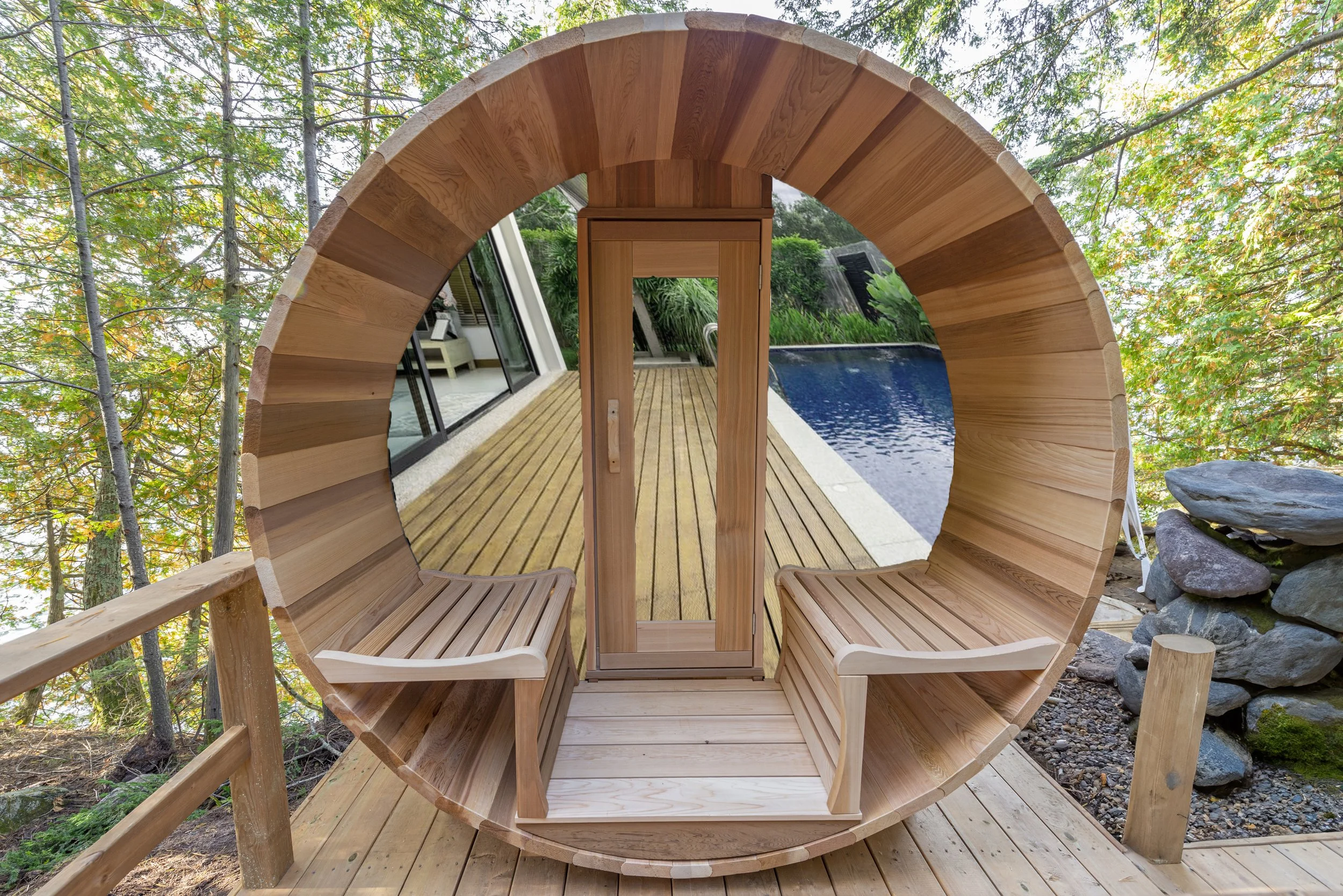 A circular wooden seating area with a backrest, overlooking a deck, pool, and lush green trees outdoors.
