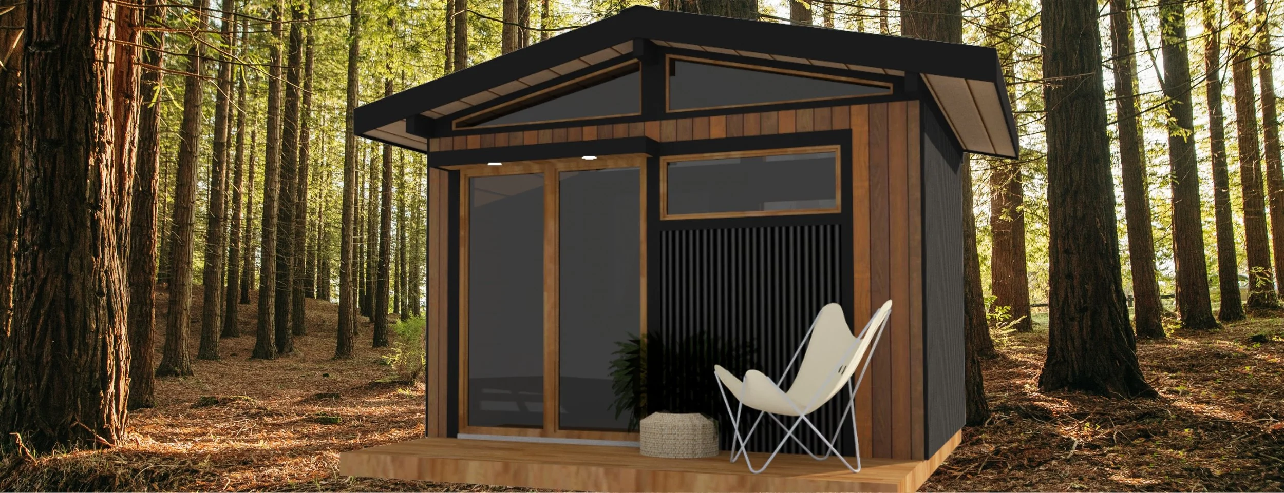 A modern tiny house with a black and wood exterior, situated in a forest with tall trees, featuring a small deck with a white chair and woven pouf.