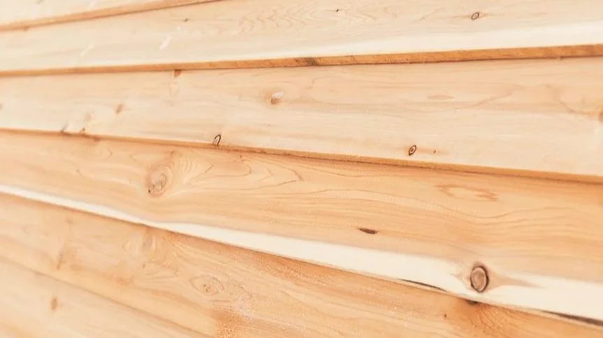 Close-up of wooden planks or siding with visible natural wood grain and knots.