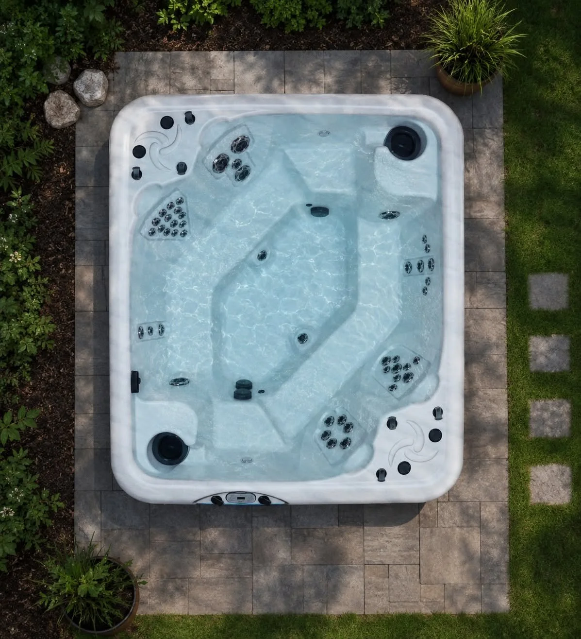 An aerial view of a white hot tub with black jets, situated on a tiled patio surrounded by greenery and potted plants.
