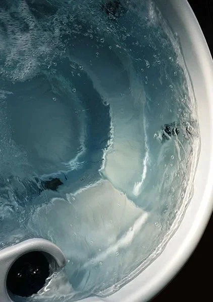 Close-up of a whirlpool tub with water swirling and bubbles forming.