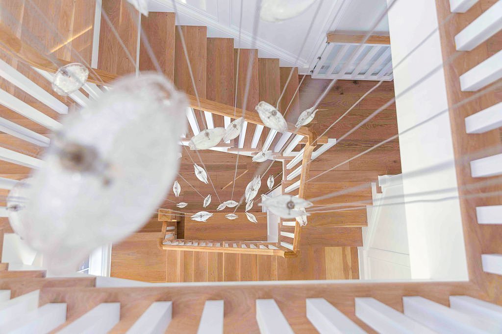 Overhead view of a spiral staircase with a modern glass and metal chandelier hanging in the center.