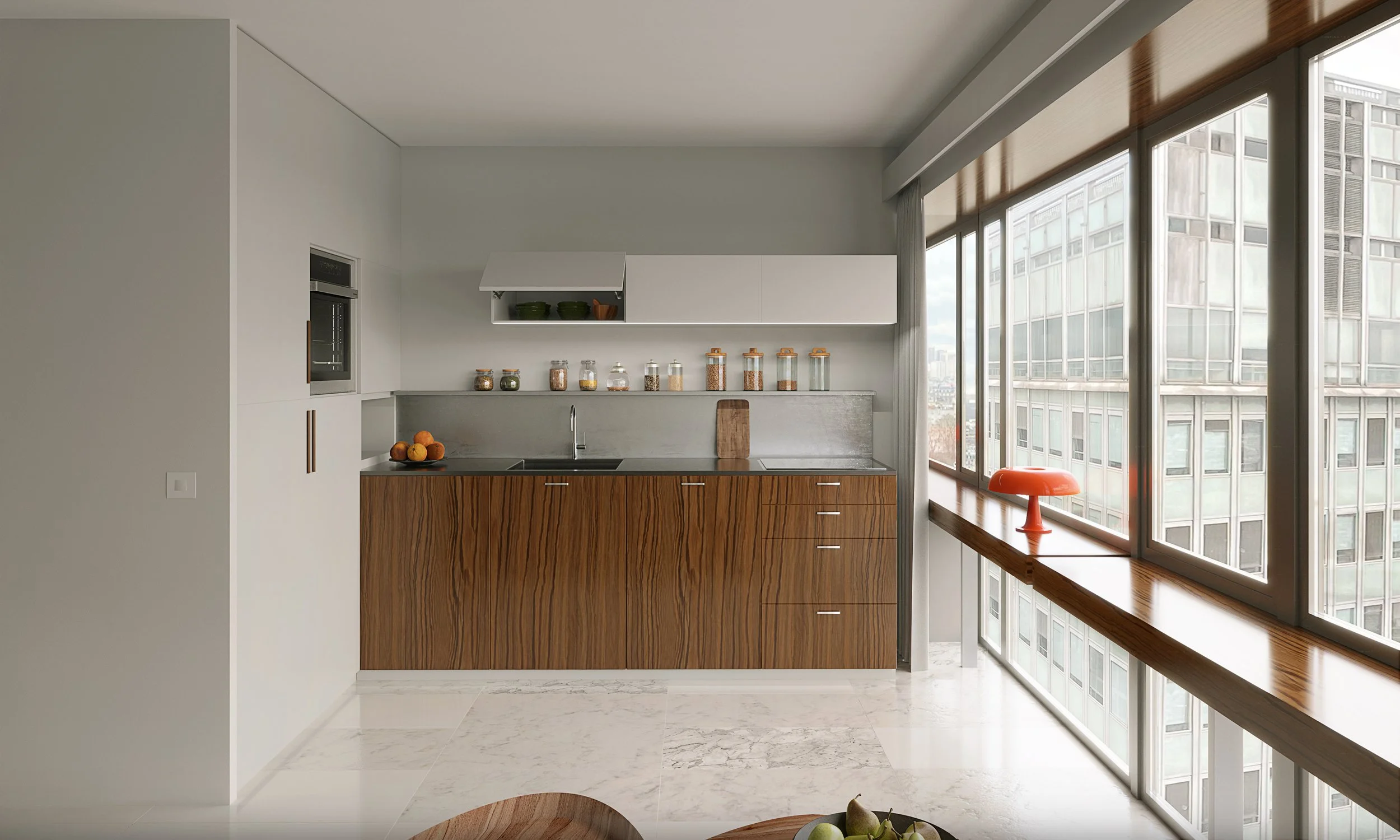 Cuisine moderne avec grands fenêtres laissant entrer beaucoup de lumière naturelle, mobilier en bois clair, étagère avec bocaux, fruits dans un bol, décoration rouge sur la table au couloir.