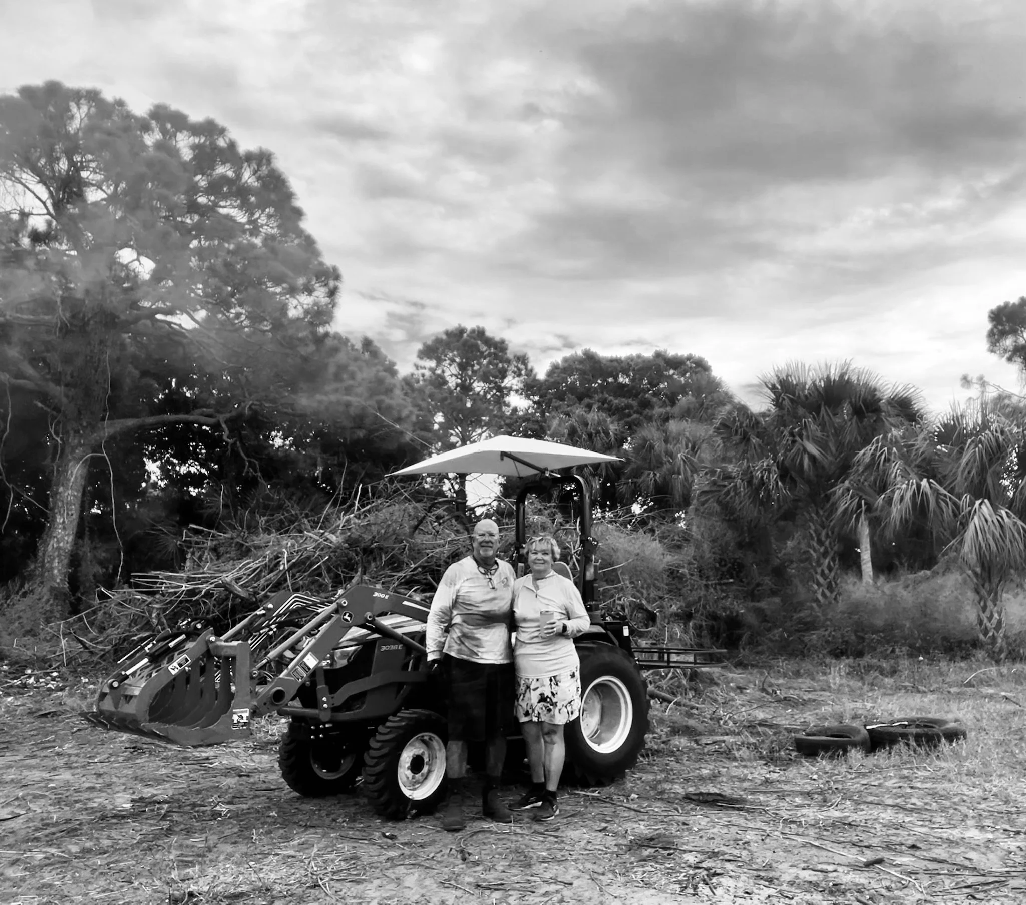 John and Debbie Lindsey with our John Deere tractor while clearing the overgrown Sawmill Farm property in Grant-Valkaria, Florida