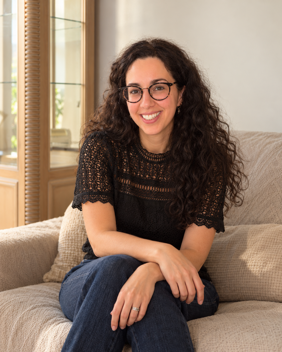Cécilia Elbaz, psychopraticienne à Levallois-Perret, assise sur un canapé beige.