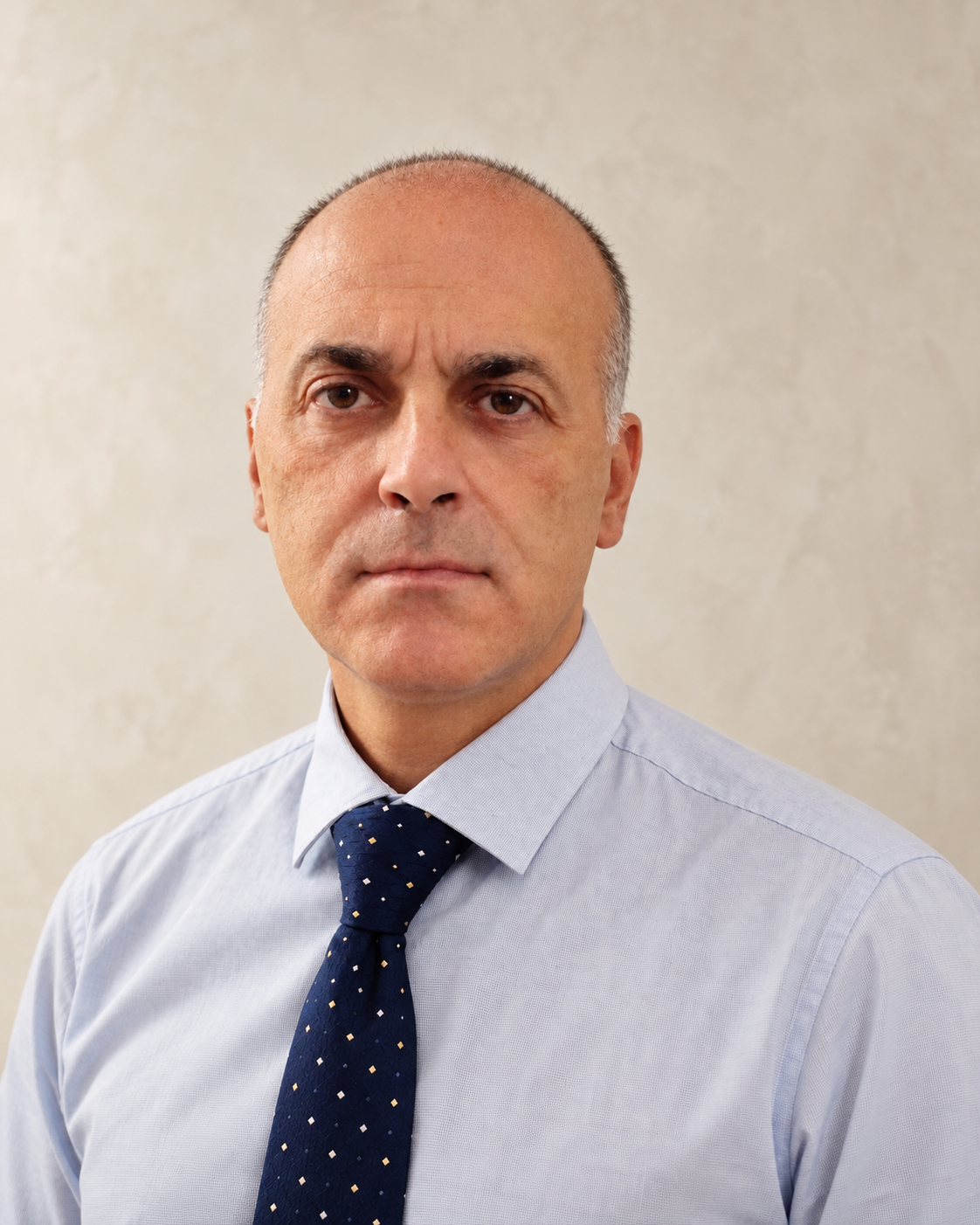 Portrait of a middle-aged man wearing a light blue dress shirt and navy patterned tie