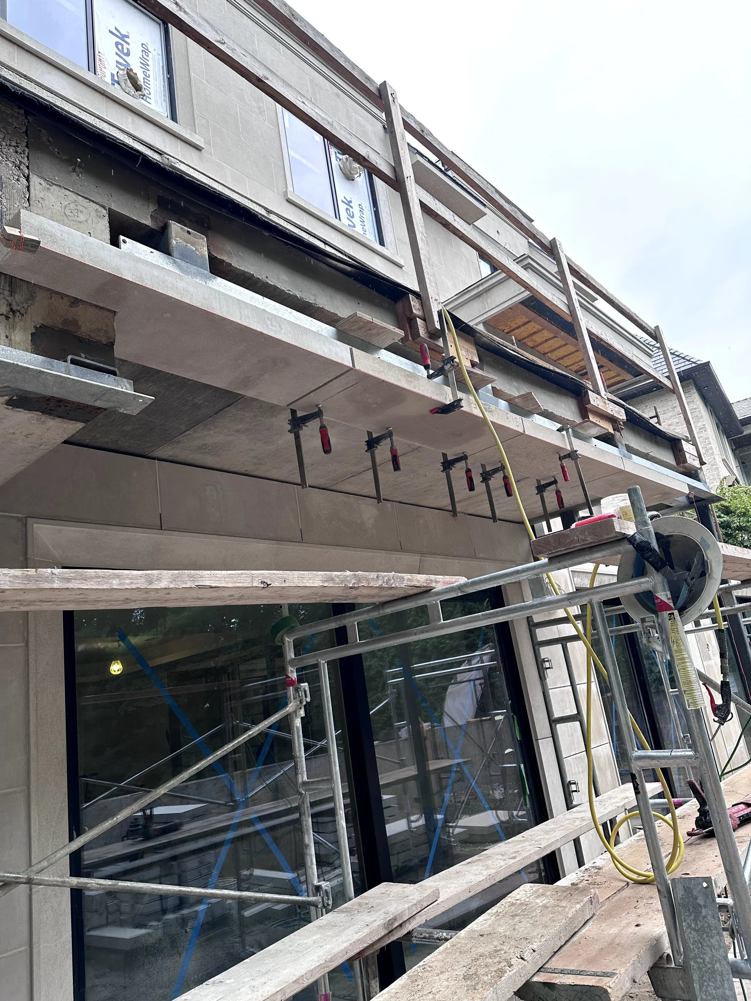 Construction site of a building with scaffolding and window installation in progress.