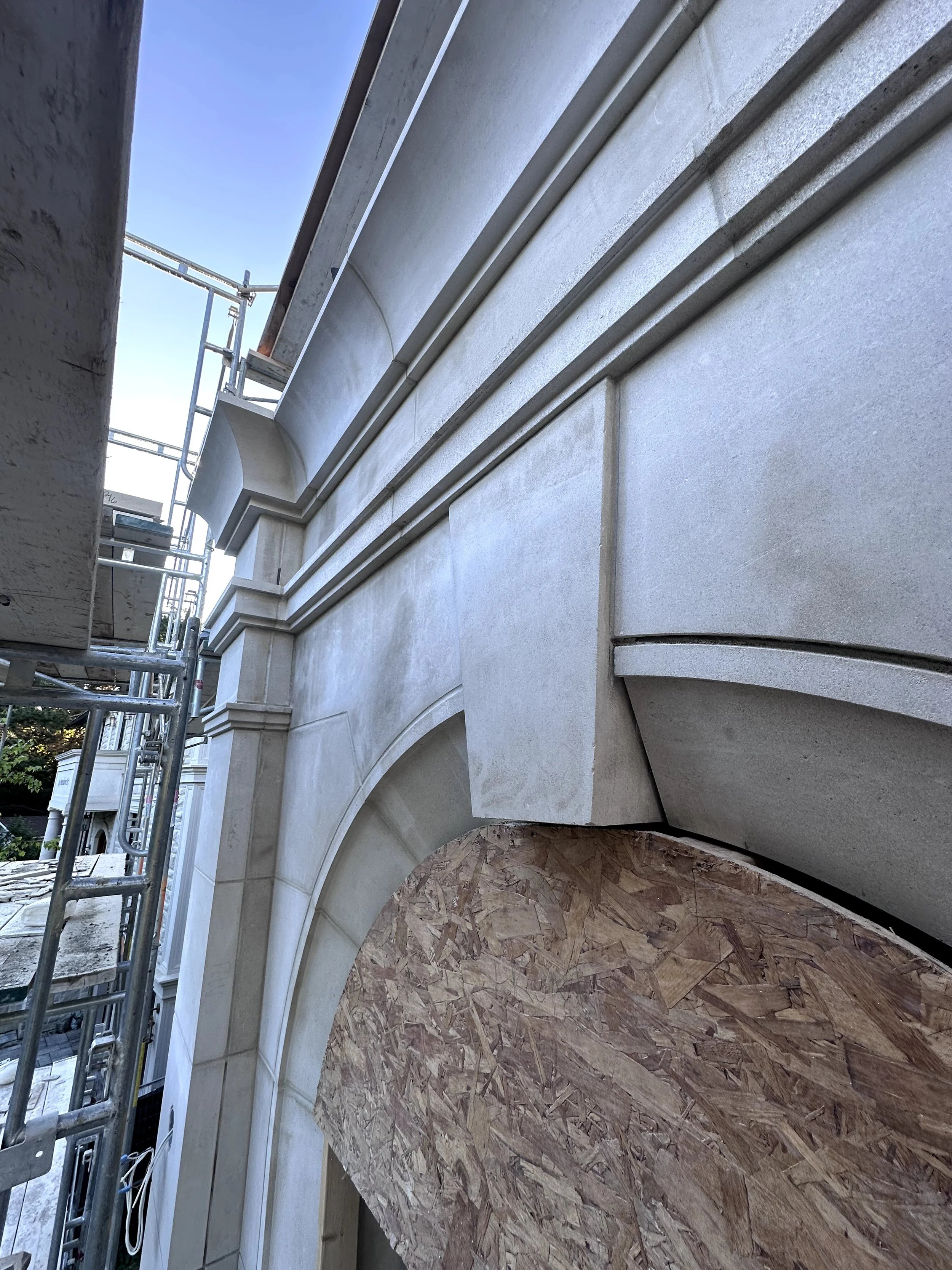 Side of a building under construction with stone and scaffolding, view from ground level looking up.