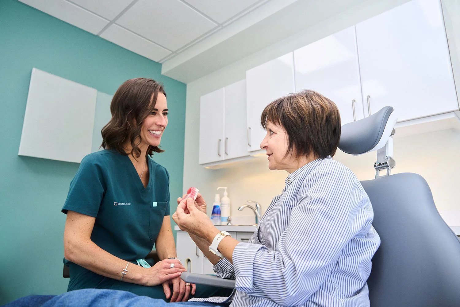 Dentiste discutant avec une patiente assise dans un fauteuil dentaire, en cabinet.