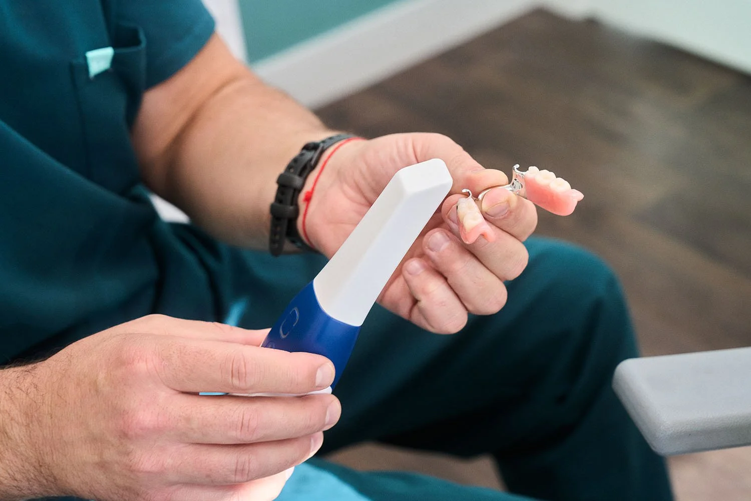 Dentiste examinant une prothèse dentaire amovible avec un instrument professionnel