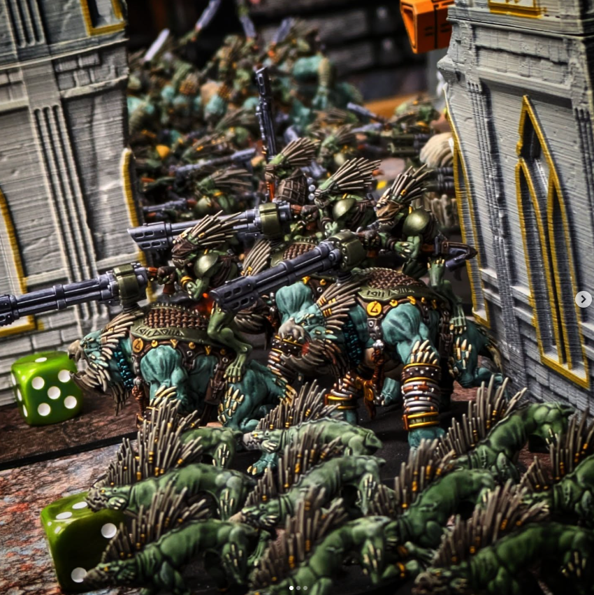 Miniature figures of orcs and goblins in a battle scene, surrounded by stone structures and green dice.