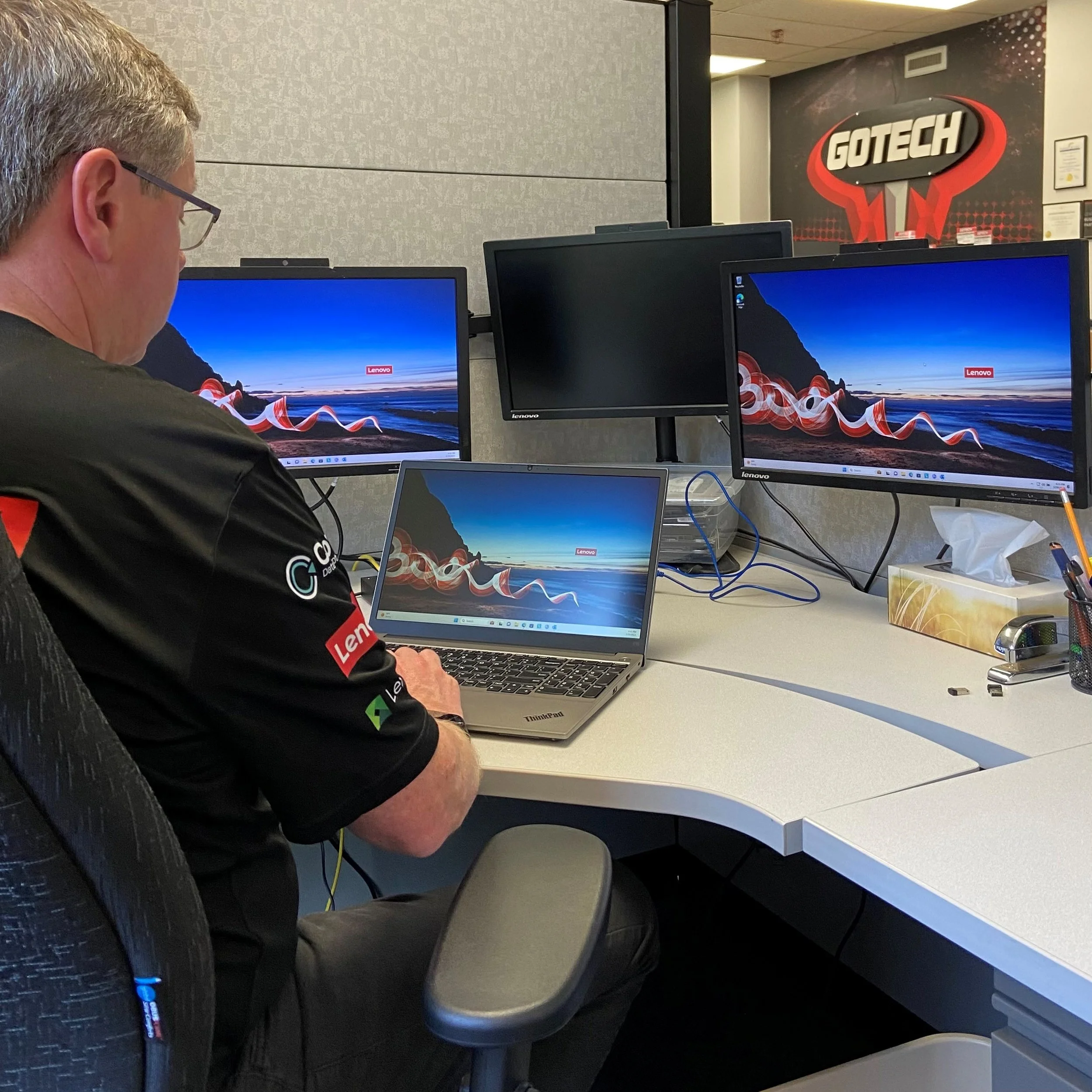 One of our human techs working on a computer with multiple monitors in an office.  Waiting to support your IT needs.
