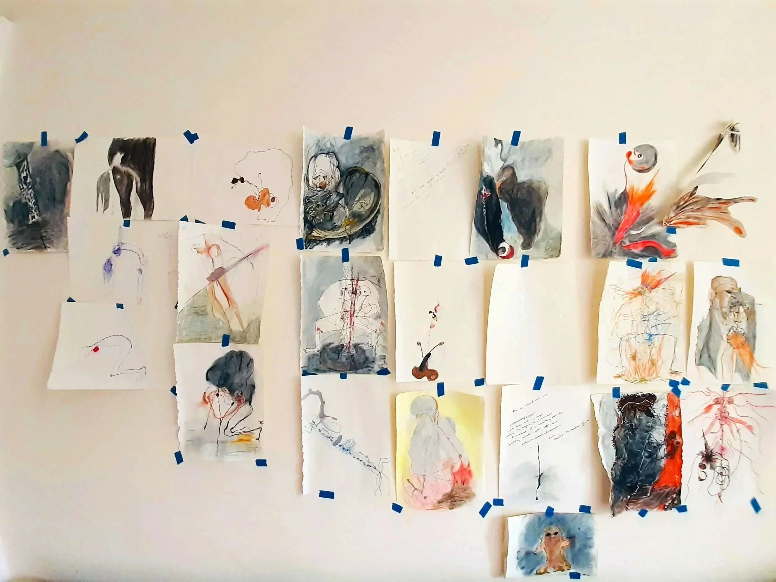 A collection of various abstract sketches and paintings, taped to a wall with blue tape. The artworks feature a mix of swirling colors, lines, and figures, some resembling animals or human forms.