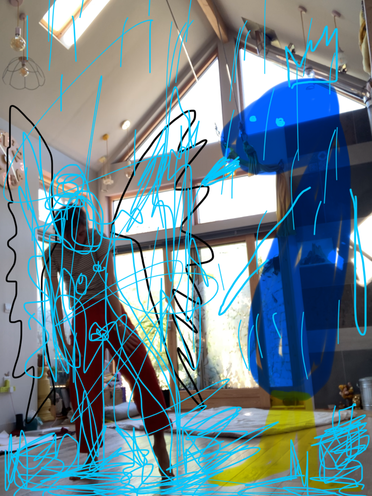 A person implementing vertical spray paint art on a large, blue, abstract sculpture inside a room with large windows.