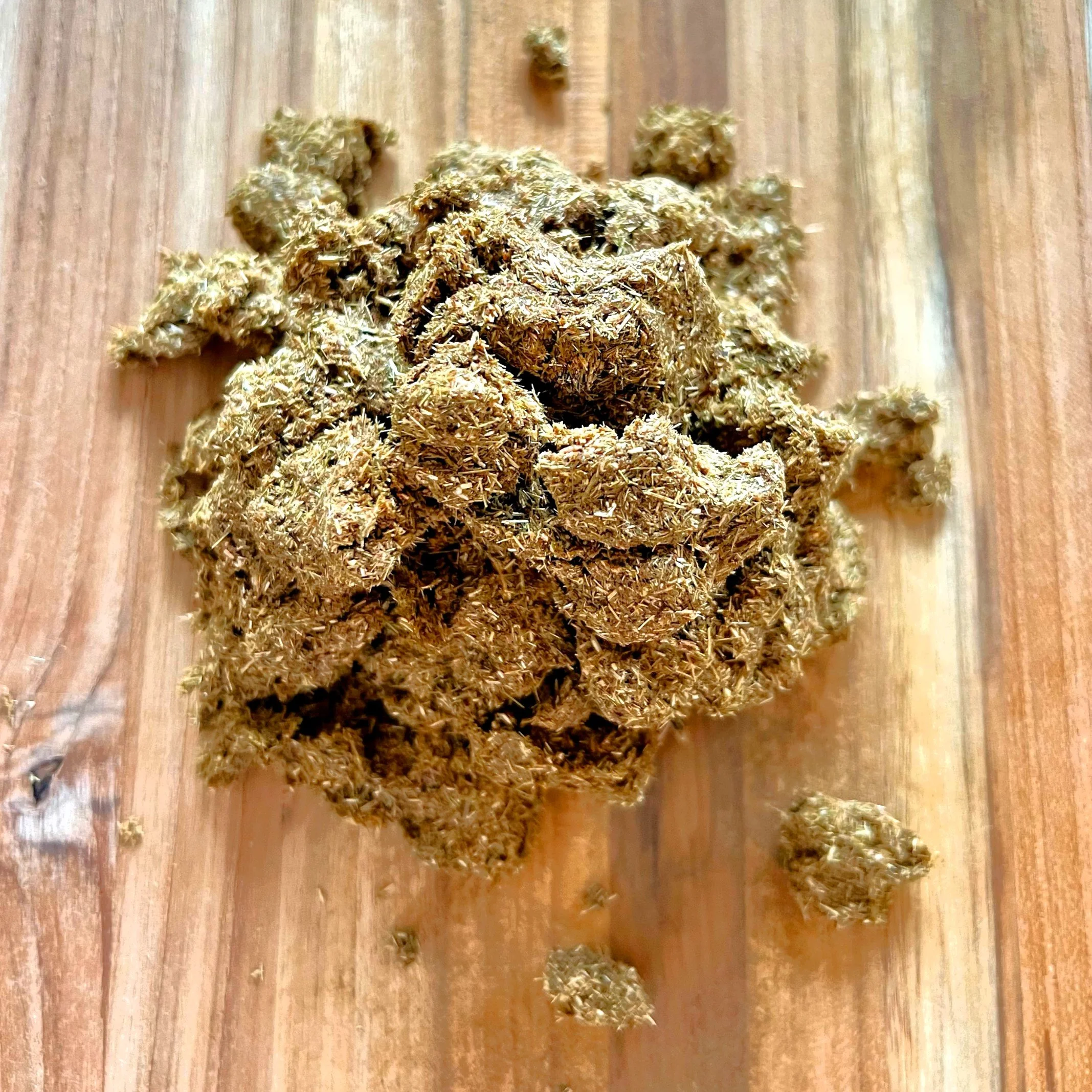 A close-up of cannabis buds placed on a wooden surface.