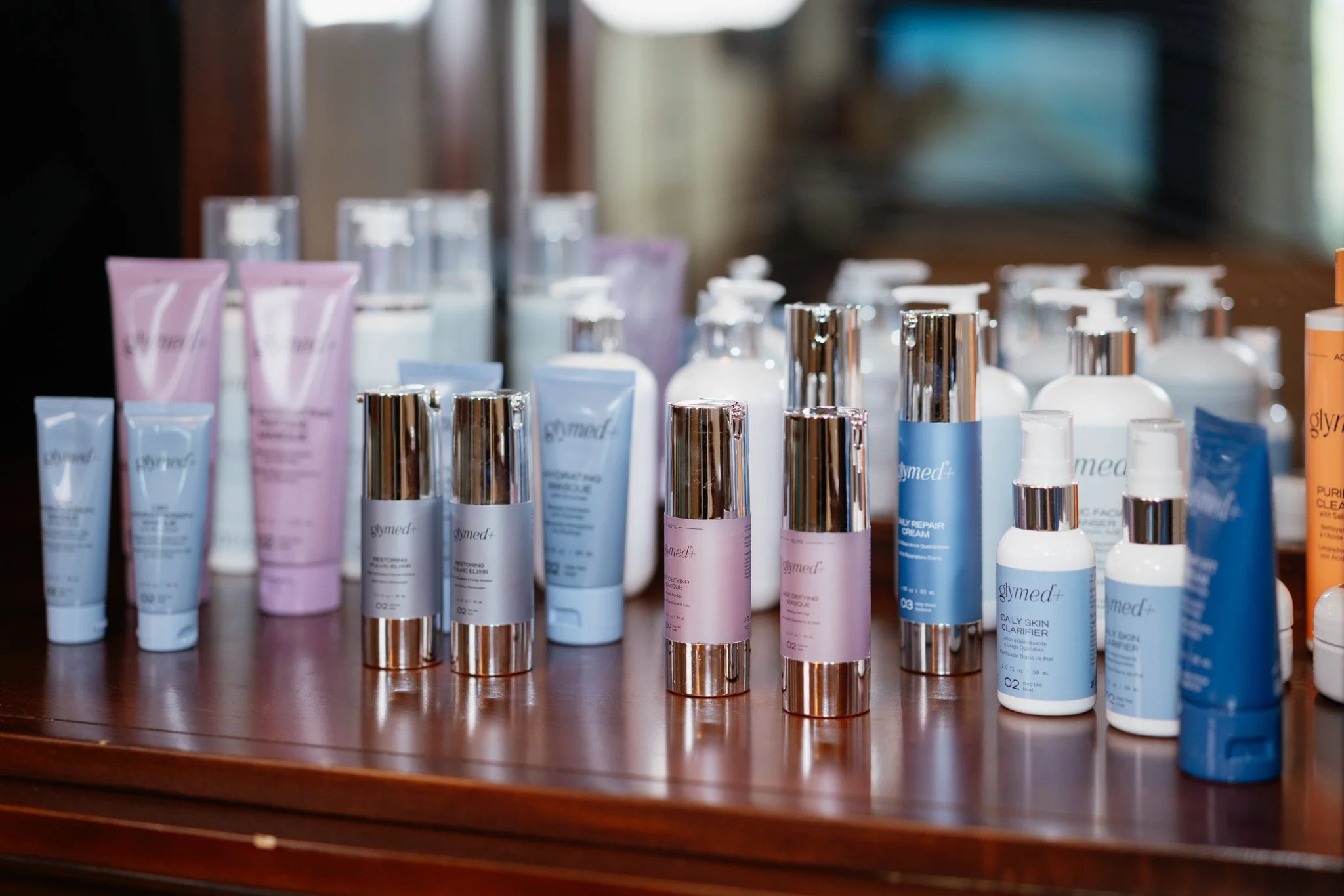 Collection of skincare bottles and tubes on a wooden surface, with labels and metallic caps.