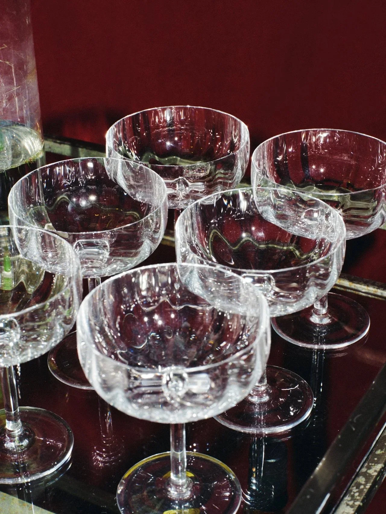 Crystal glasses of red wine on a reflective surface against a deep red background